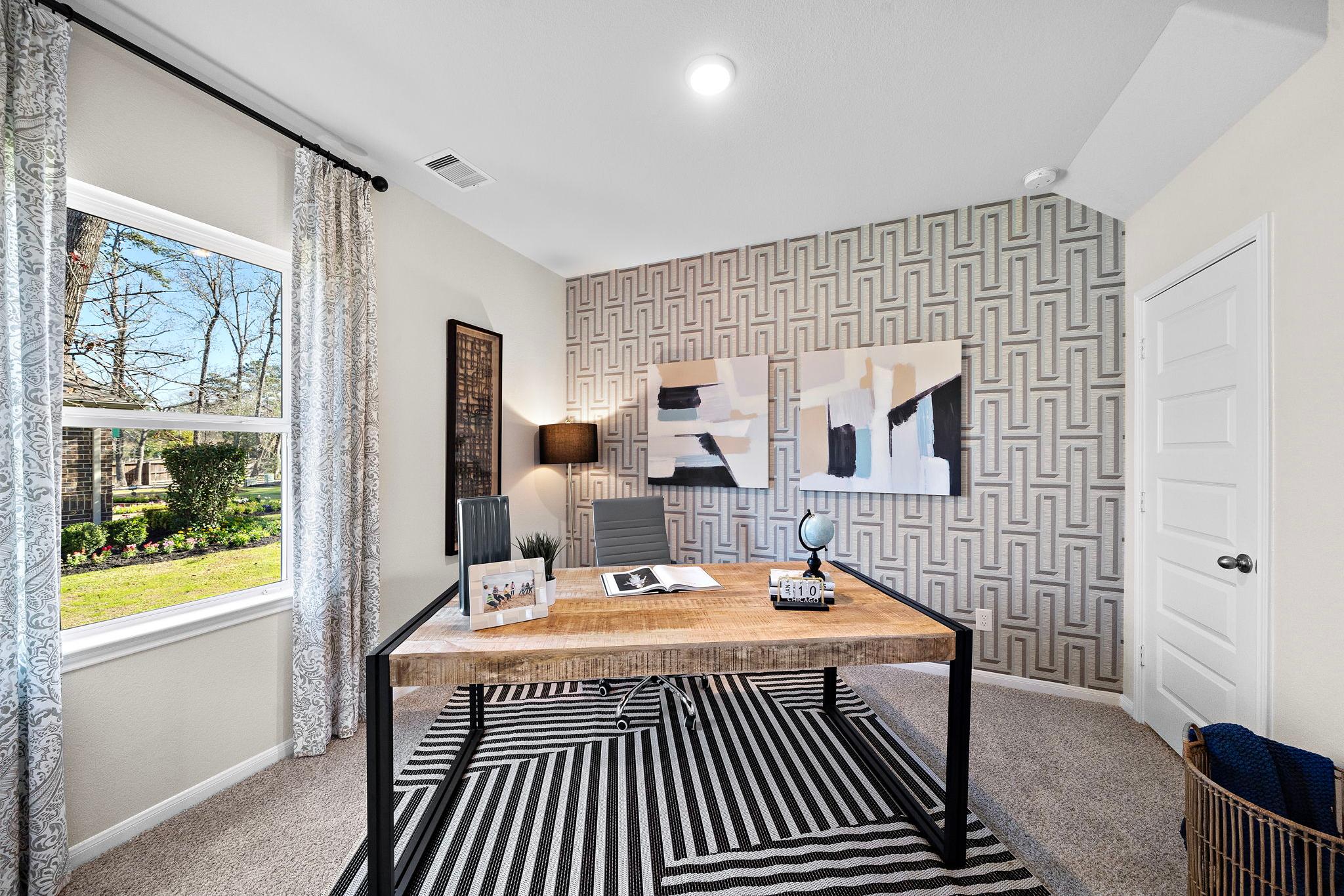 Contemporary home office at Lakes at Black Oak in Magnolia Texas with wooden desk geometric wallpaper large windows and abstract art