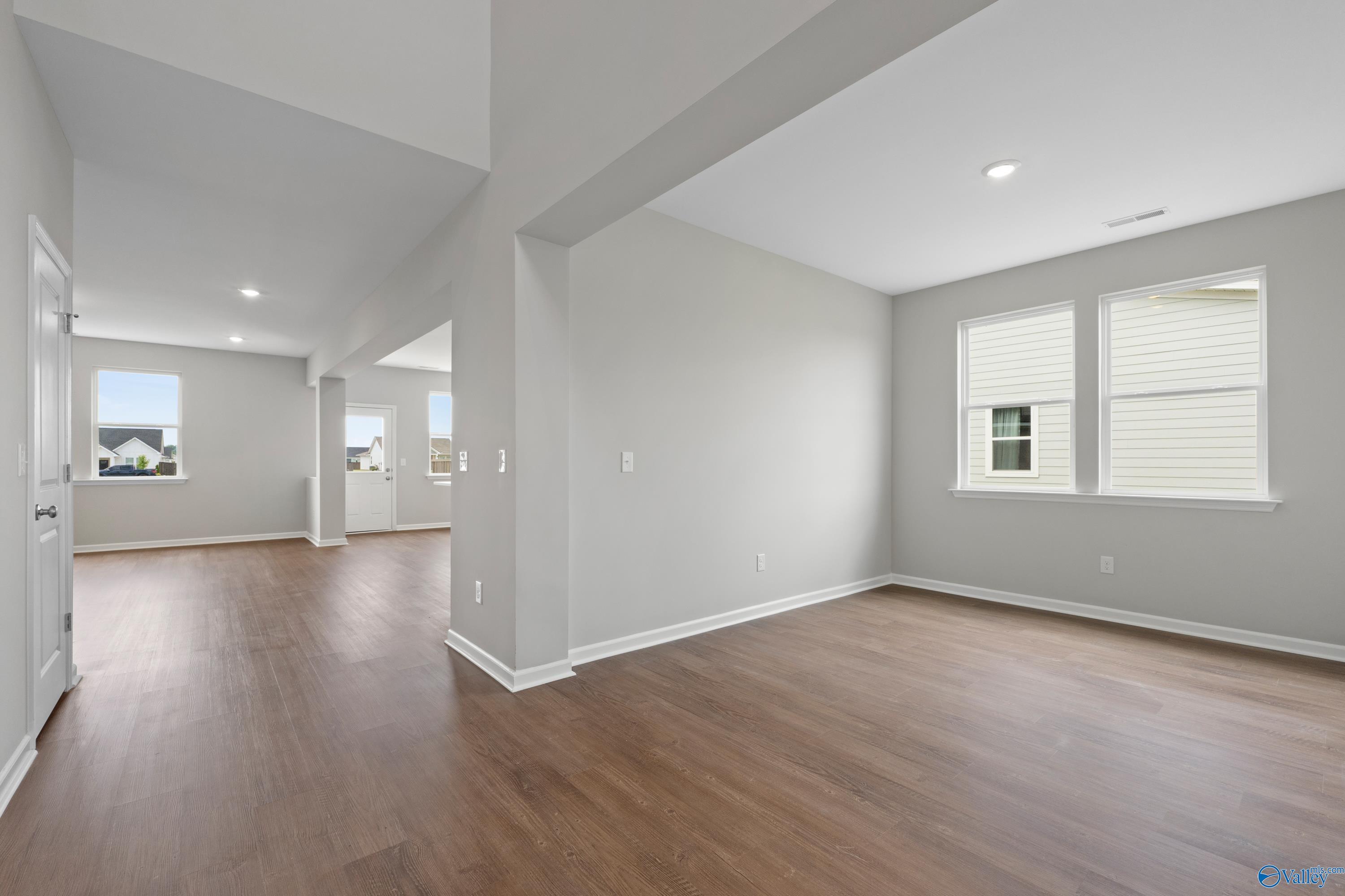 Spacious open hallway with dark hardwood floors, light gray walls, and large windows in Davidson Homes The Dorado, Athens Alabama