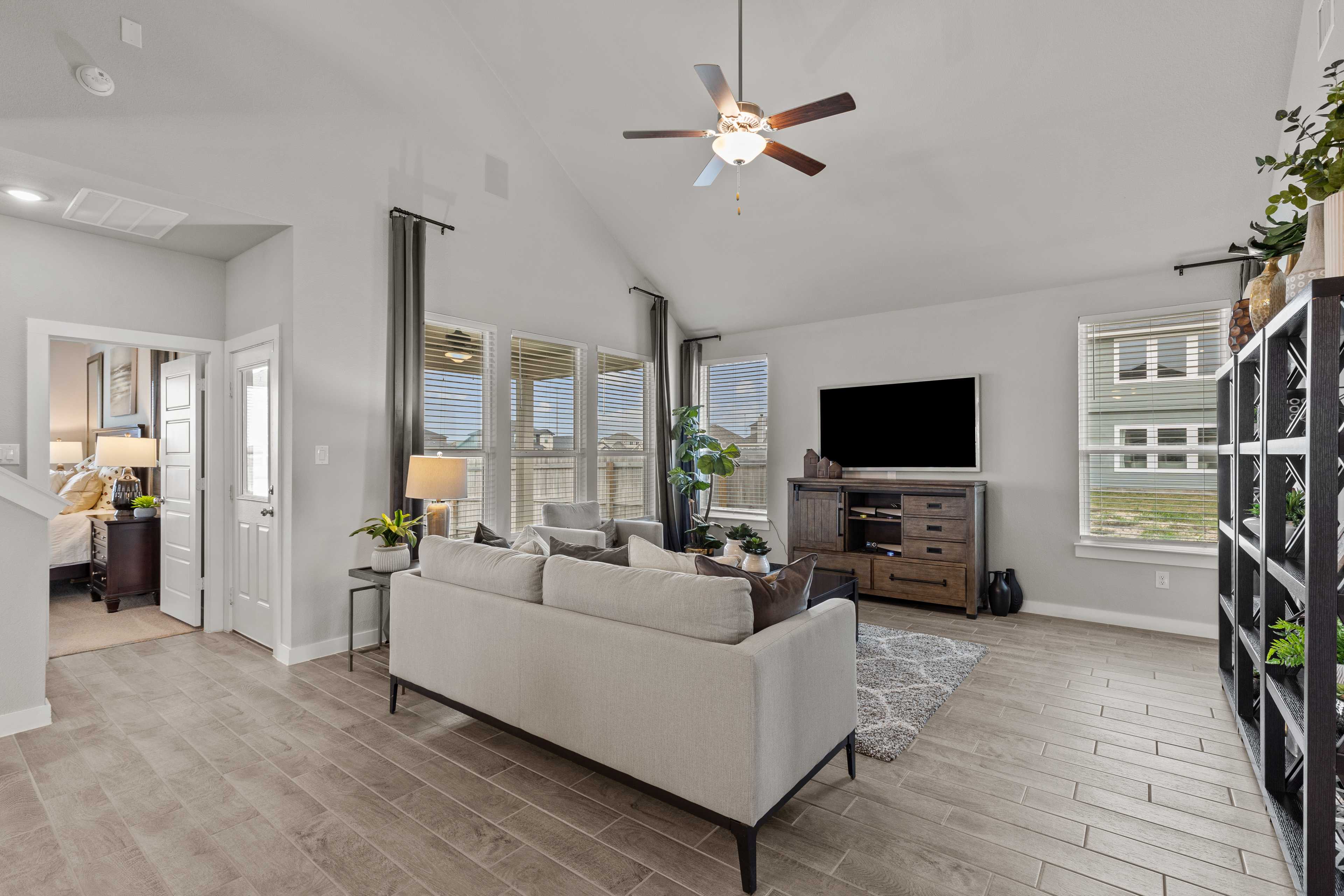 Spacious open-concept living room at Hannah Heights in Seguin Texas with beige sofa, hardwood floors, large windows, and ceiling fan
