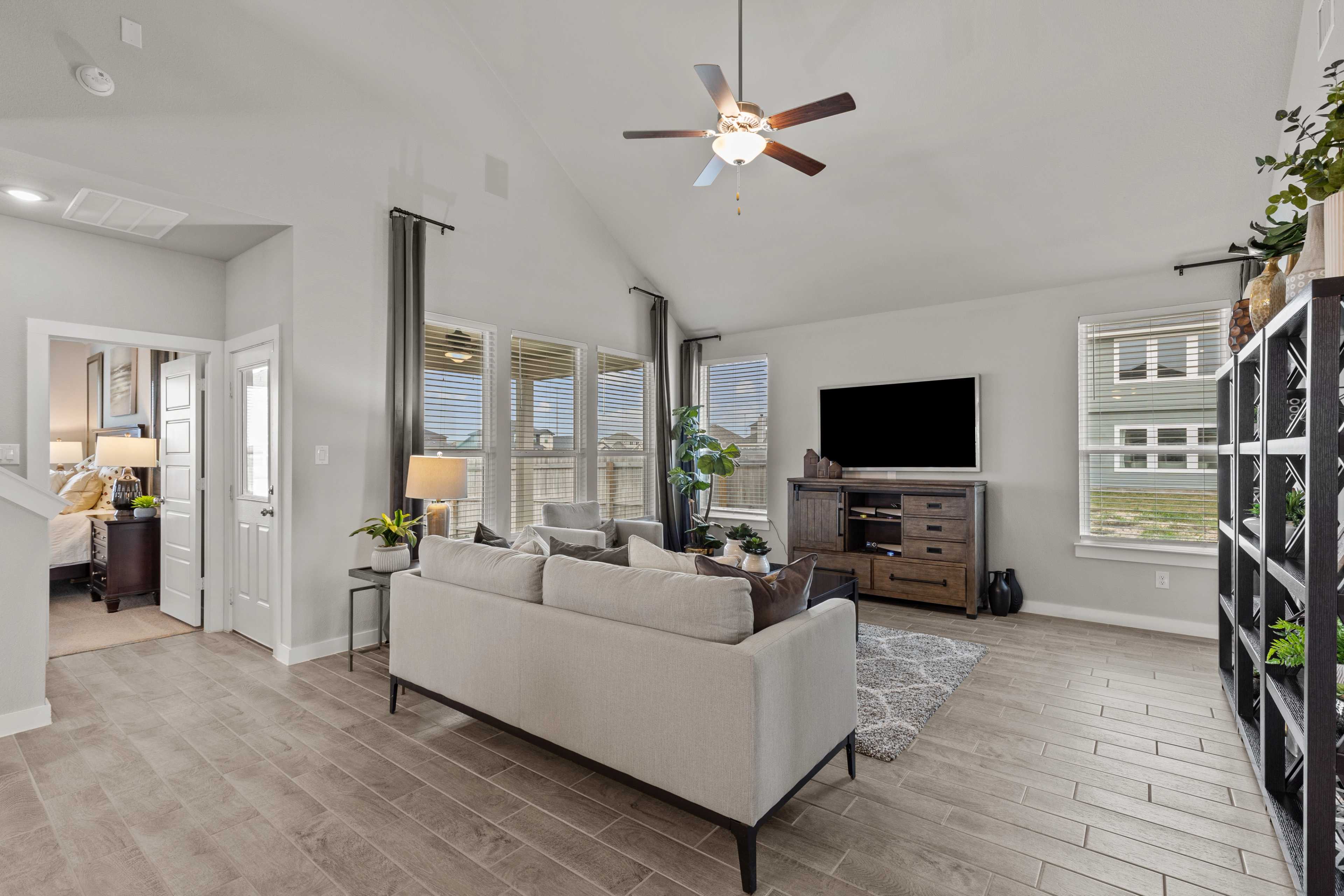 Spacious open-concept living room at Hannah Heights in Seguin Texas with beige sofa, hardwood floors, large windows, and ceiling fan