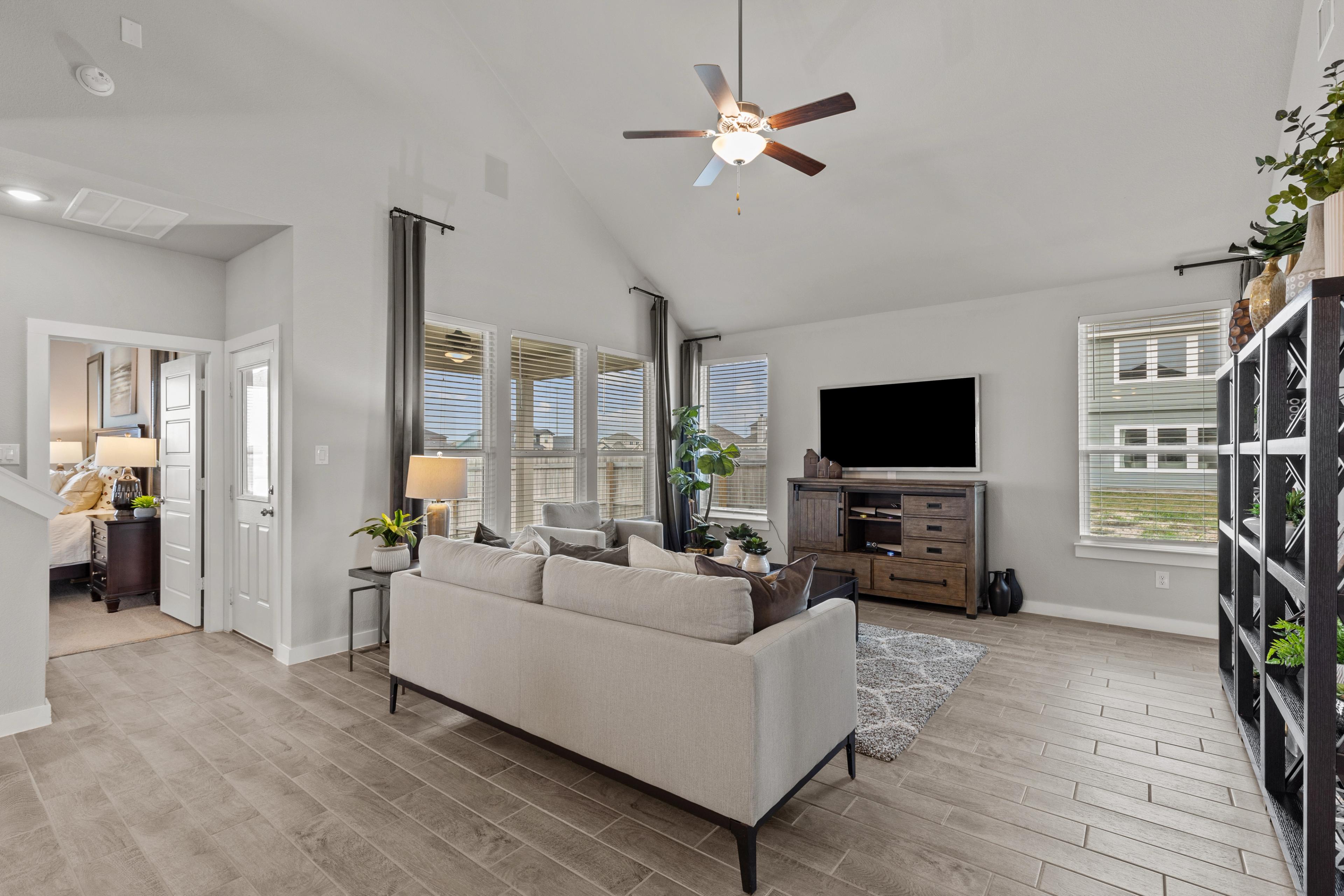 Spacious open-concept living room at Hannah Heights in Seguin Texas with beige sofa, hardwood floors, large windows, and ceiling fan