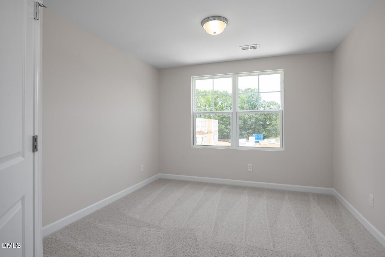 Bright, neutral-toned bedroom in The Graham floor plan at Springvale, Fuquay-Varina, featuring plush carpet and natural light.