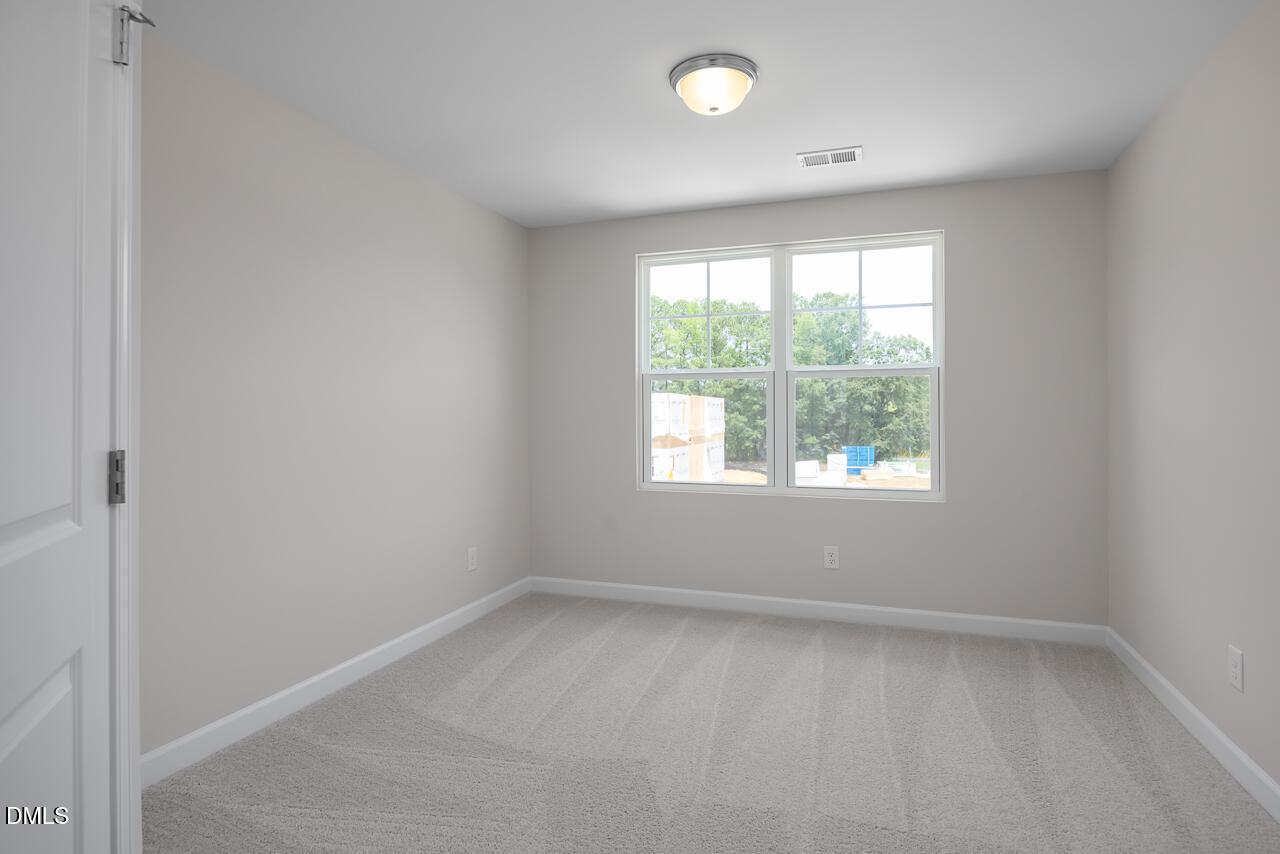 Bright, neutral-toned bedroom in The Graham floor plan at Springvale, Fuquay-Varina, featuring plush carpet and natural light.