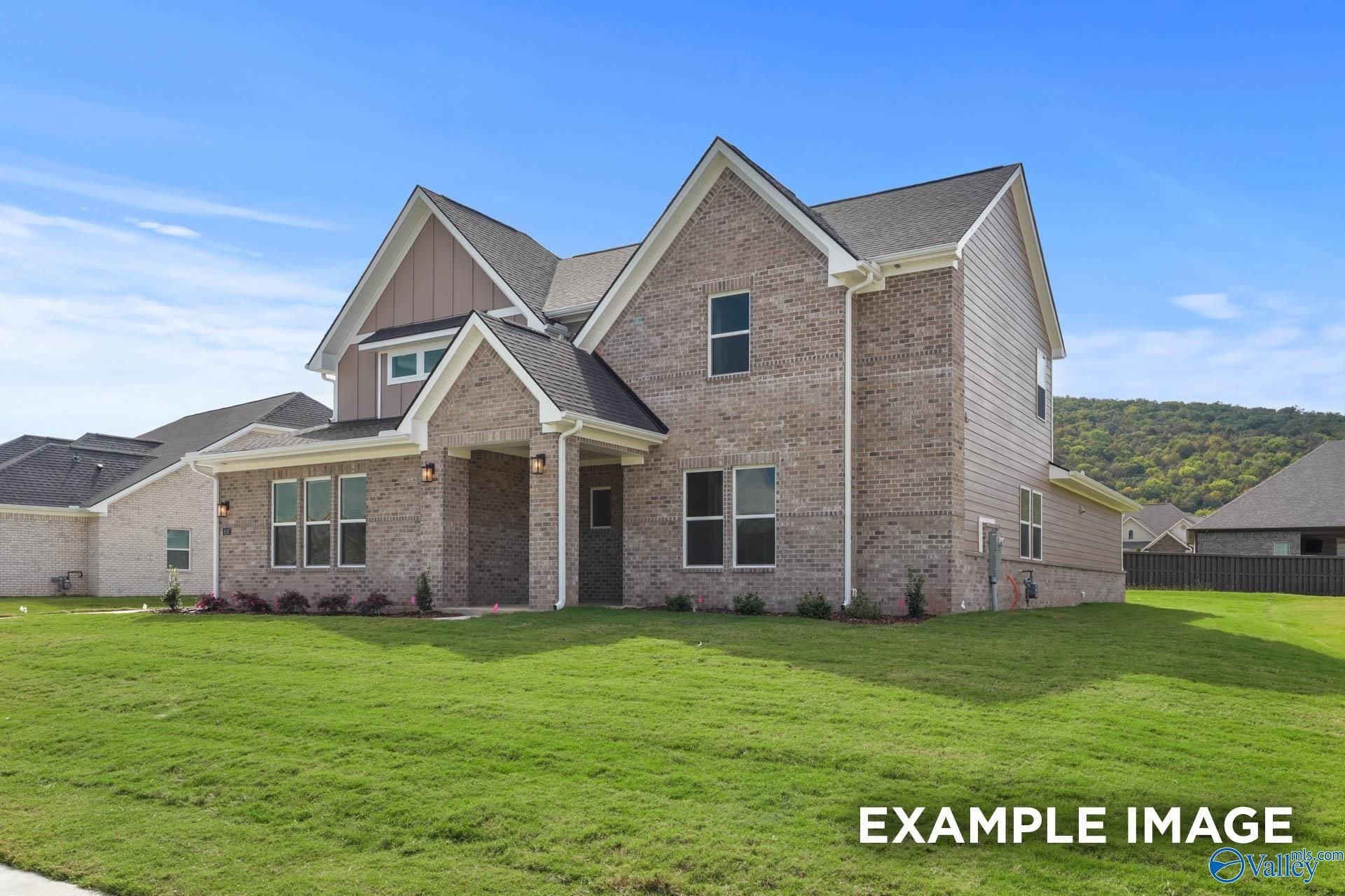 Two-story brick home with shake siding, gabled roof, front porch, lush green lawn in The Meadows at Hampton Cove, Owens Cross Roads, AL