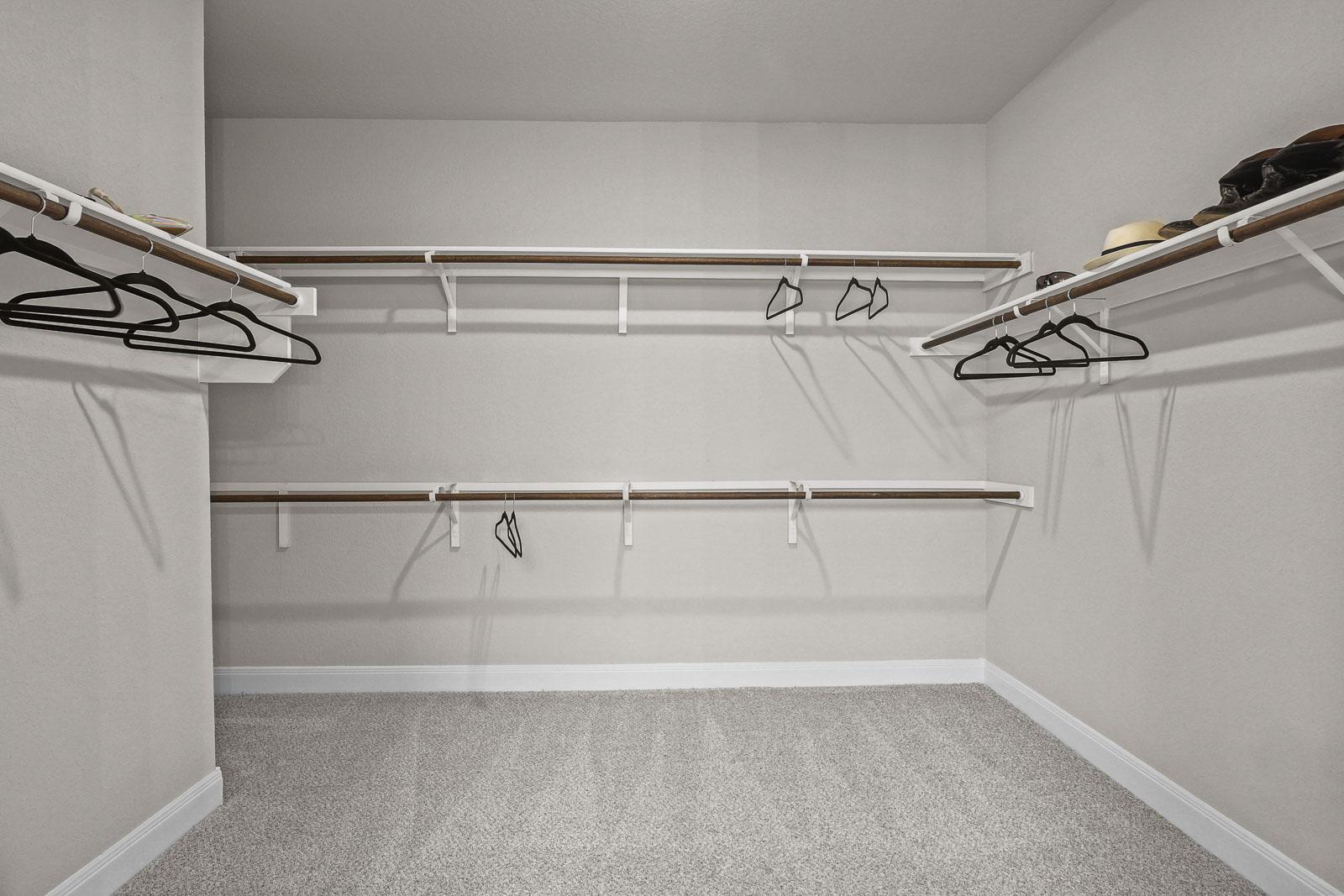 Spacious walk-in closet with tiered shelving and carpeted floors in The Jennings G master suite by Davidson Homes.