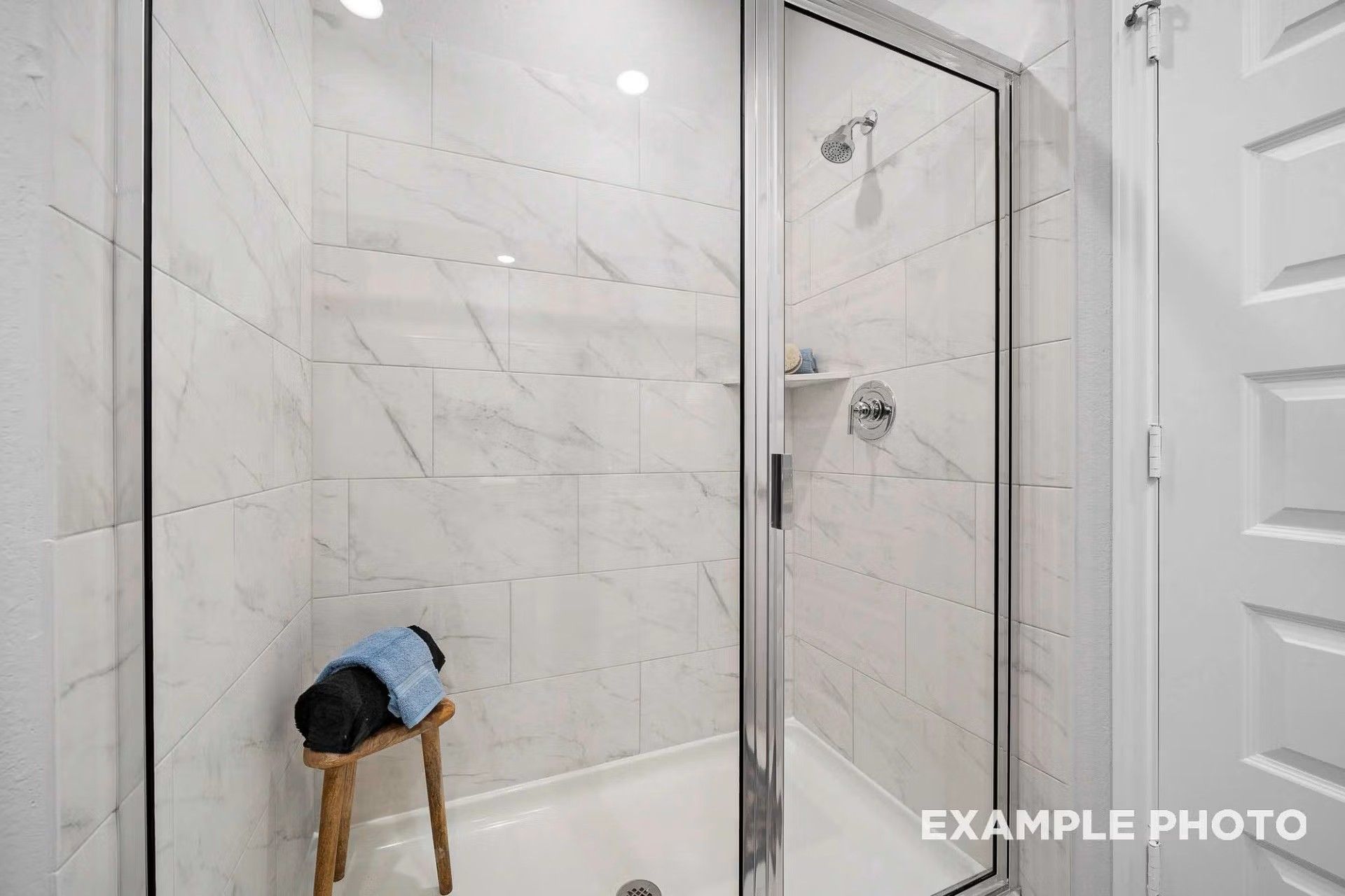 Modern walk-in shower with white marble-look tile and glass door in The San Marcos E floor plan, Heartland, Texas.