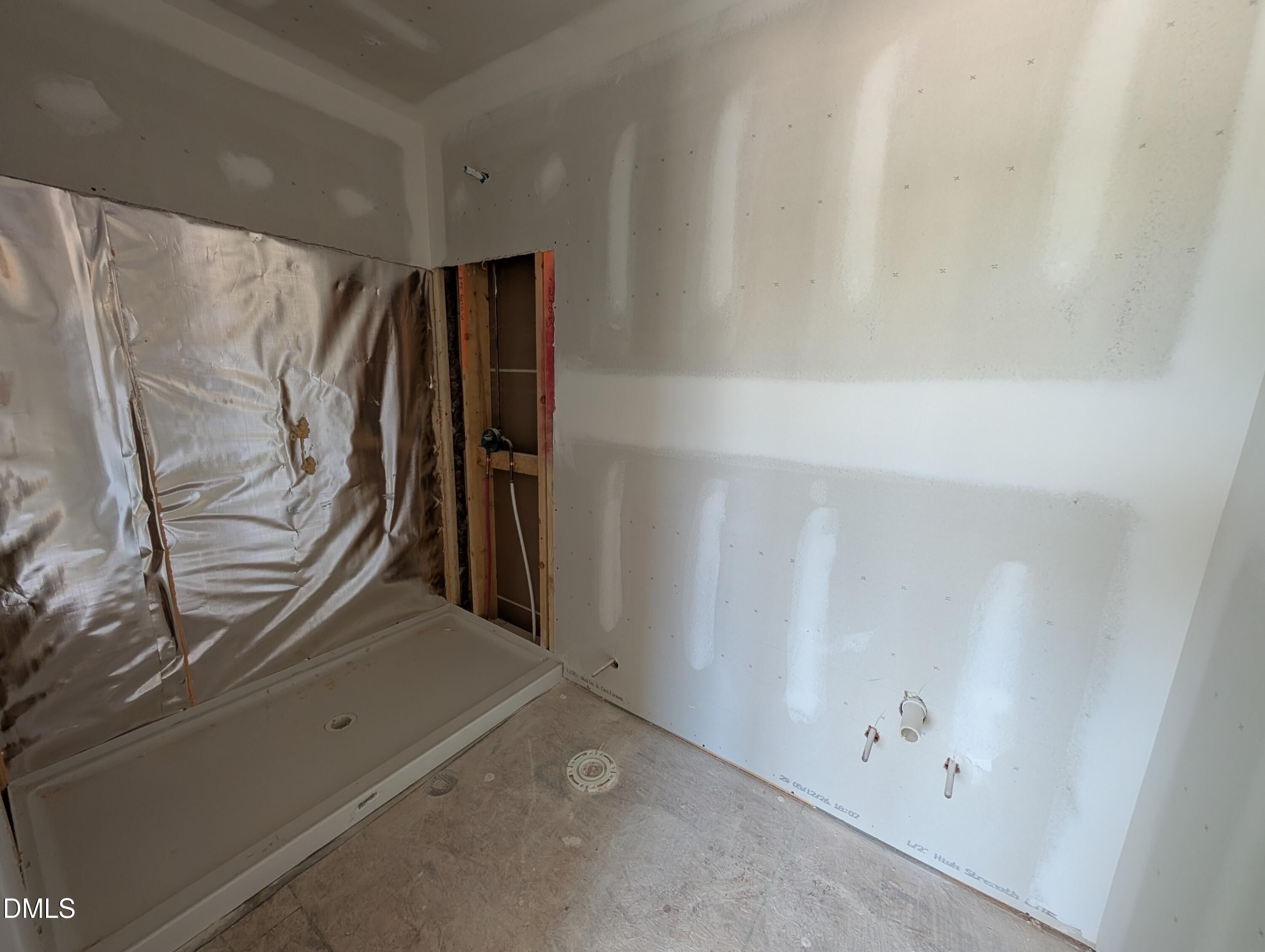 Unfinished bathroom under construction with shower base and plumbing in The Chestnut floor plan at Wendell Ridge.