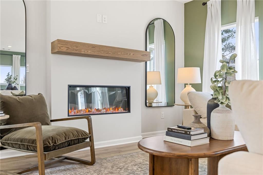 Modern electric fireplace with wooden mantel in the Rabun B floor plan living room at The Bluffs in Canton, Georgia.