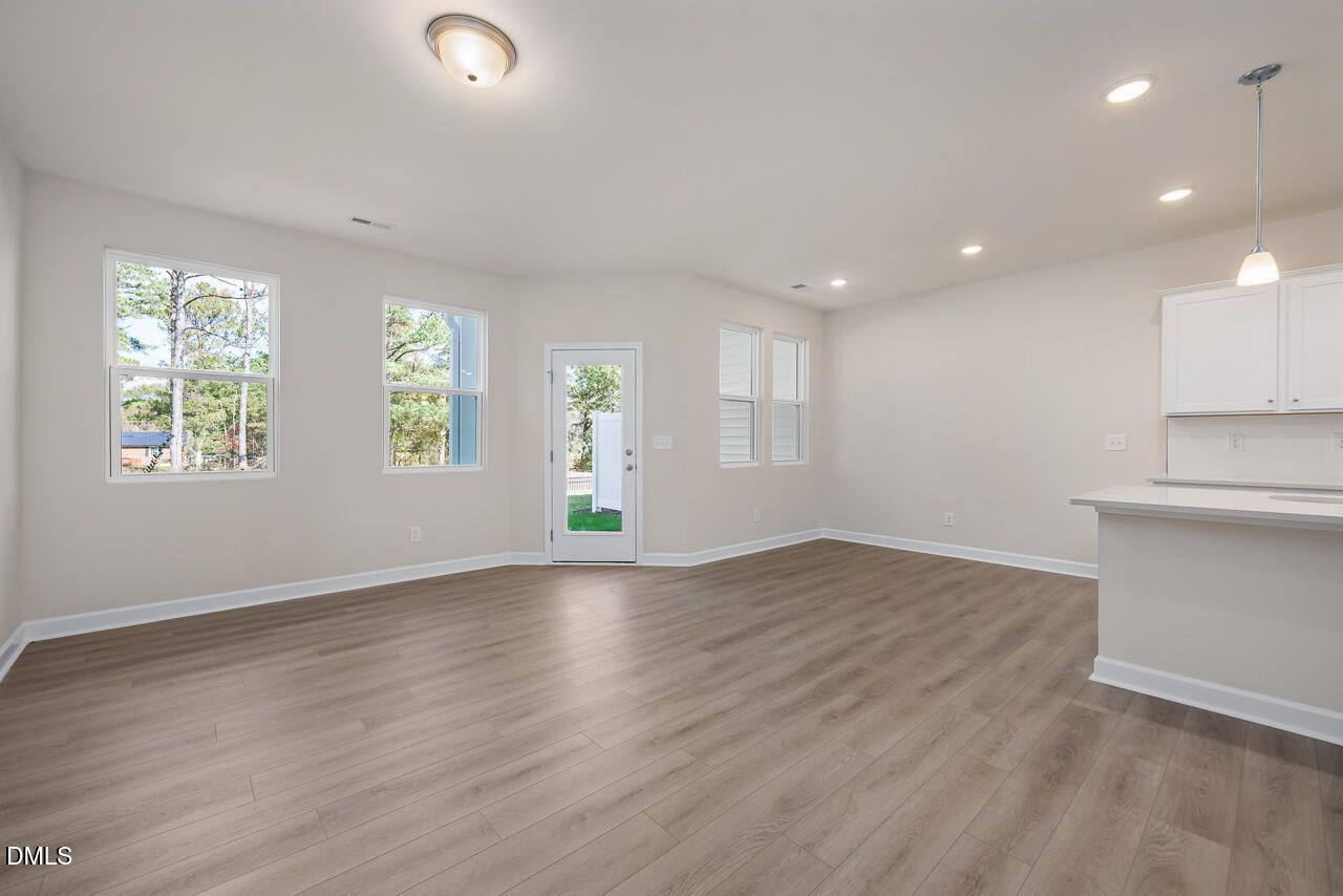 Bright open-concept living area with hardwood floors, white cabinets, and French doors to backyard in Davidson Homes The Graham, Fuquay-Varina, NC