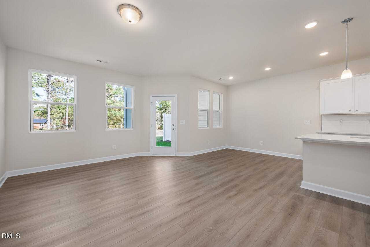 Bright open-concept living area with hardwood floors, white cabinets, and French doors to backyard in Davidson Homes The Graham, Fuquay-Varina, NC