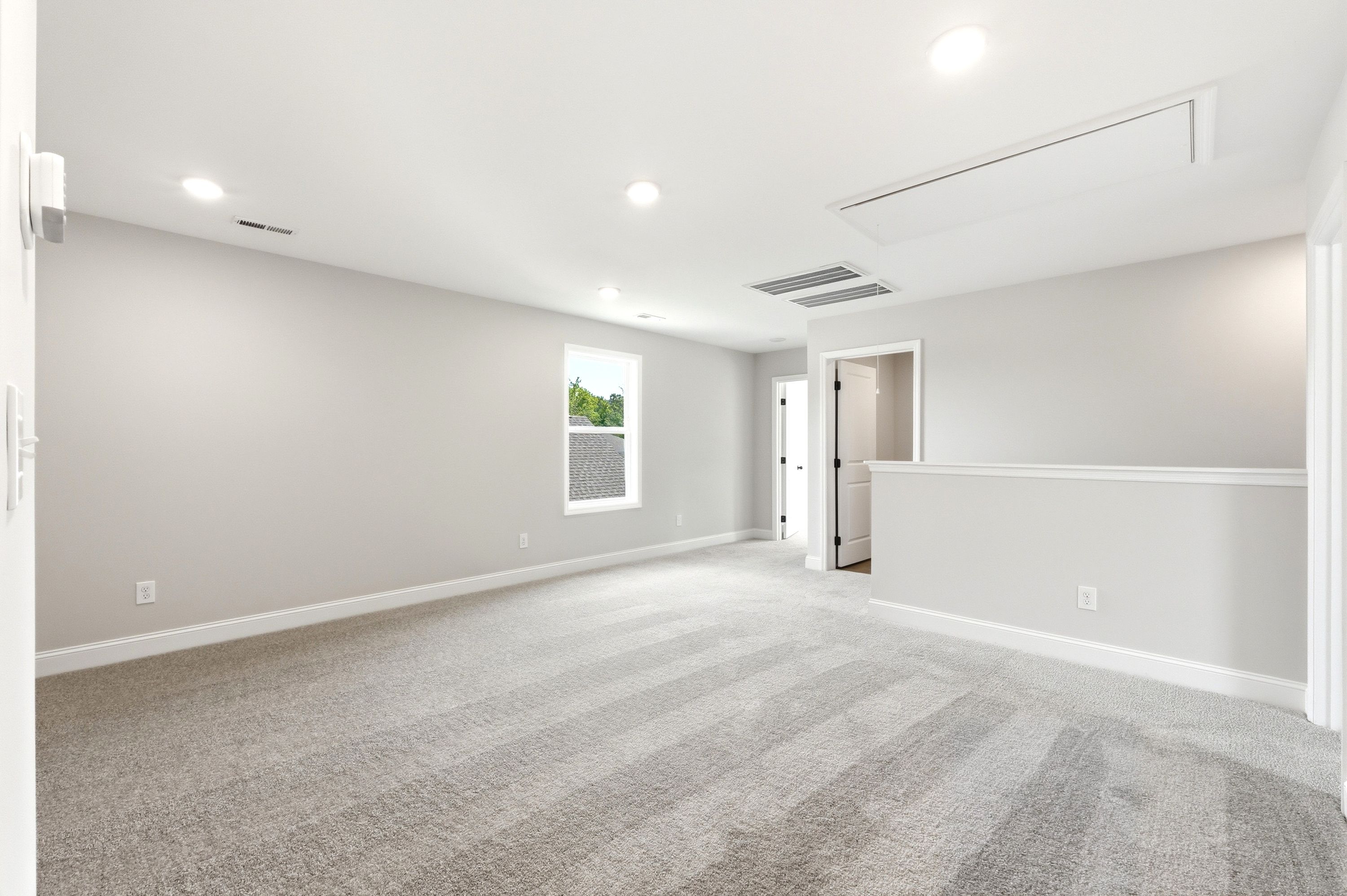 Spacious upper-level loft in The Russell A floor plan featuring neutral paint, plush carpeting, and recessed lighting.