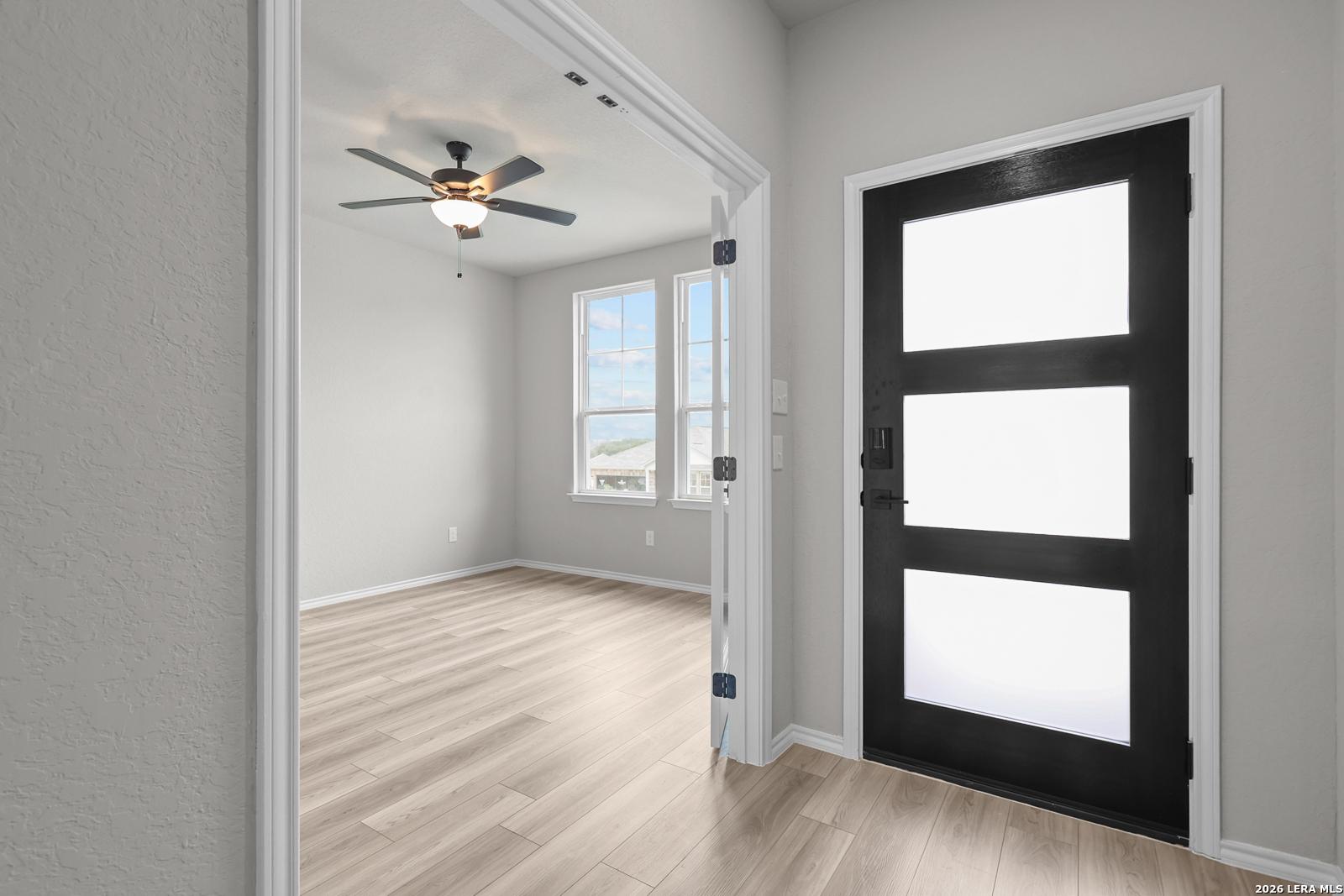 Bright entryway with ceiling fan, hardwood floors, and frosted glass front door in Davidson Homes The Glenwood F, Royal Crest, San Antonio