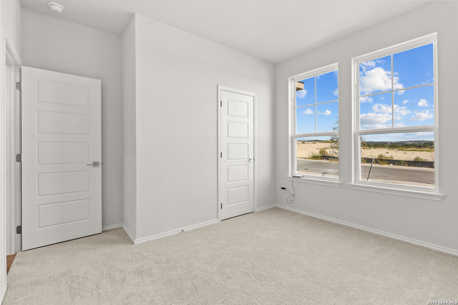 Bright carpeted bedroom with white doors and large windows at Davidson Homes' The Daphne I in Bricewood, San Antonio, Texas