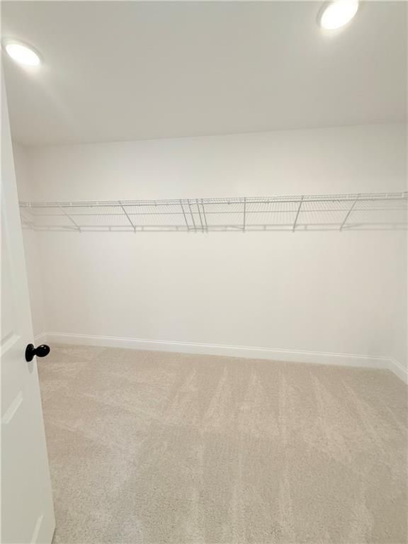 Spacious walk-in closet with wire shelving and carpeted floors in The Hickory B at Wehunt Meadows, Hoschton, Georgia.