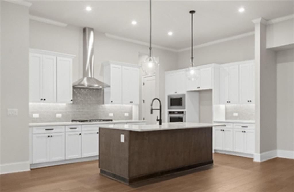Modern kitchen with white shaker cabinets, quartz island, stainless appliances, subway backsplash in Davidson Homes Seaside A, Woodstock, GA