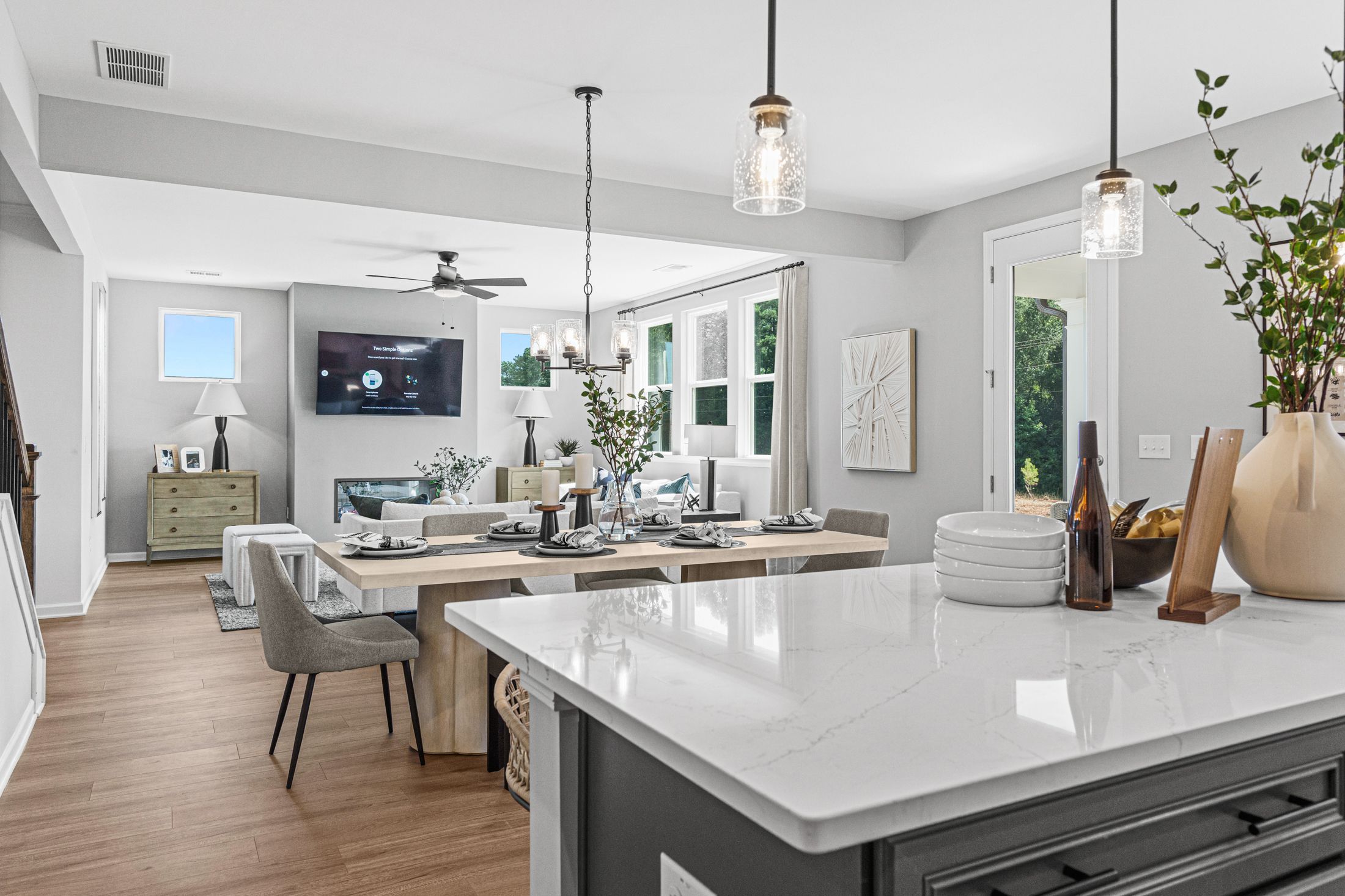 Open-concept kitchen dining living area in Fern Hollow Buford GA with white quartz island hardwood floors pendant lights
