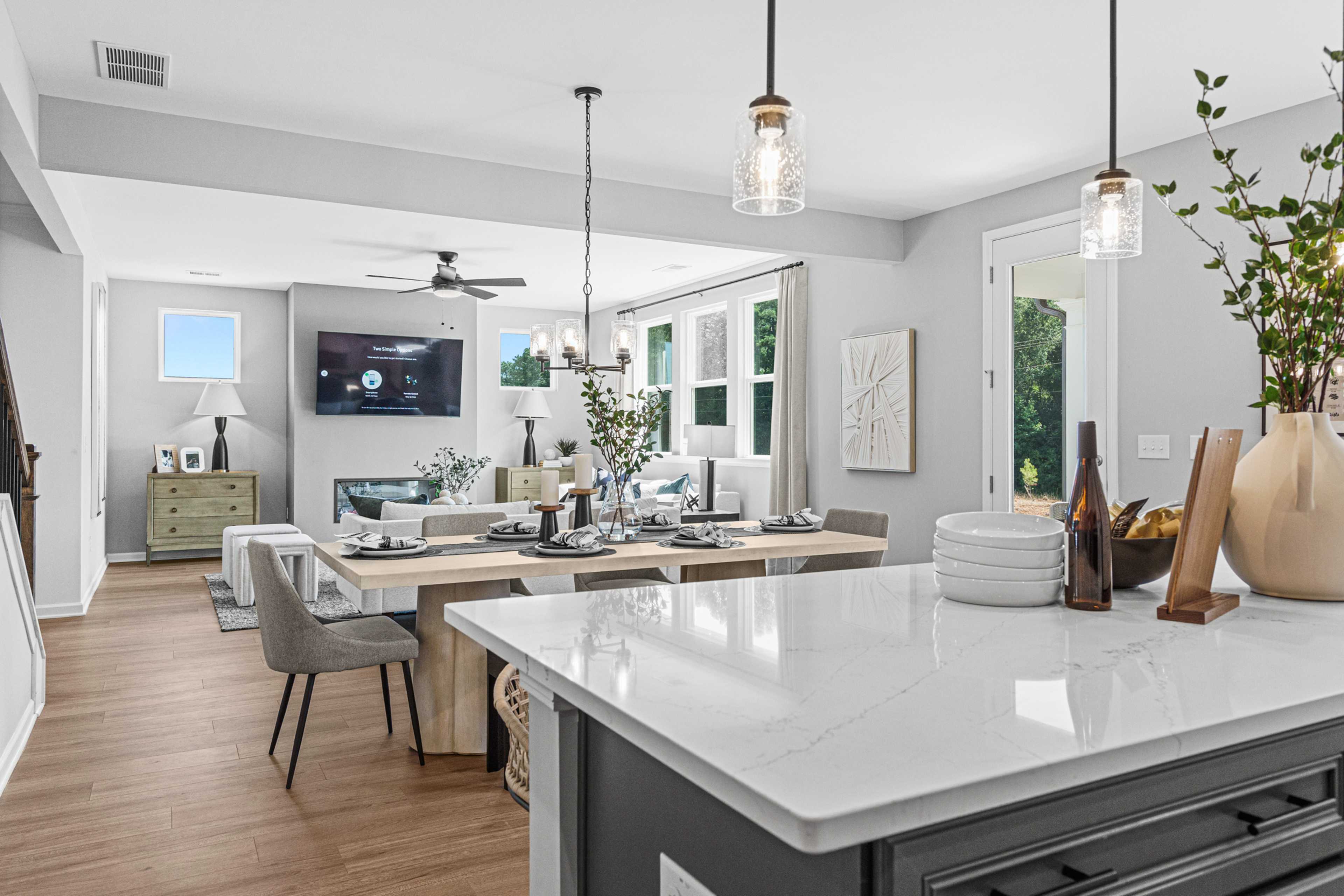 Open-concept kitchen dining living area in Fern Hollow Buford GA with white quartz island hardwood floors pendant lights