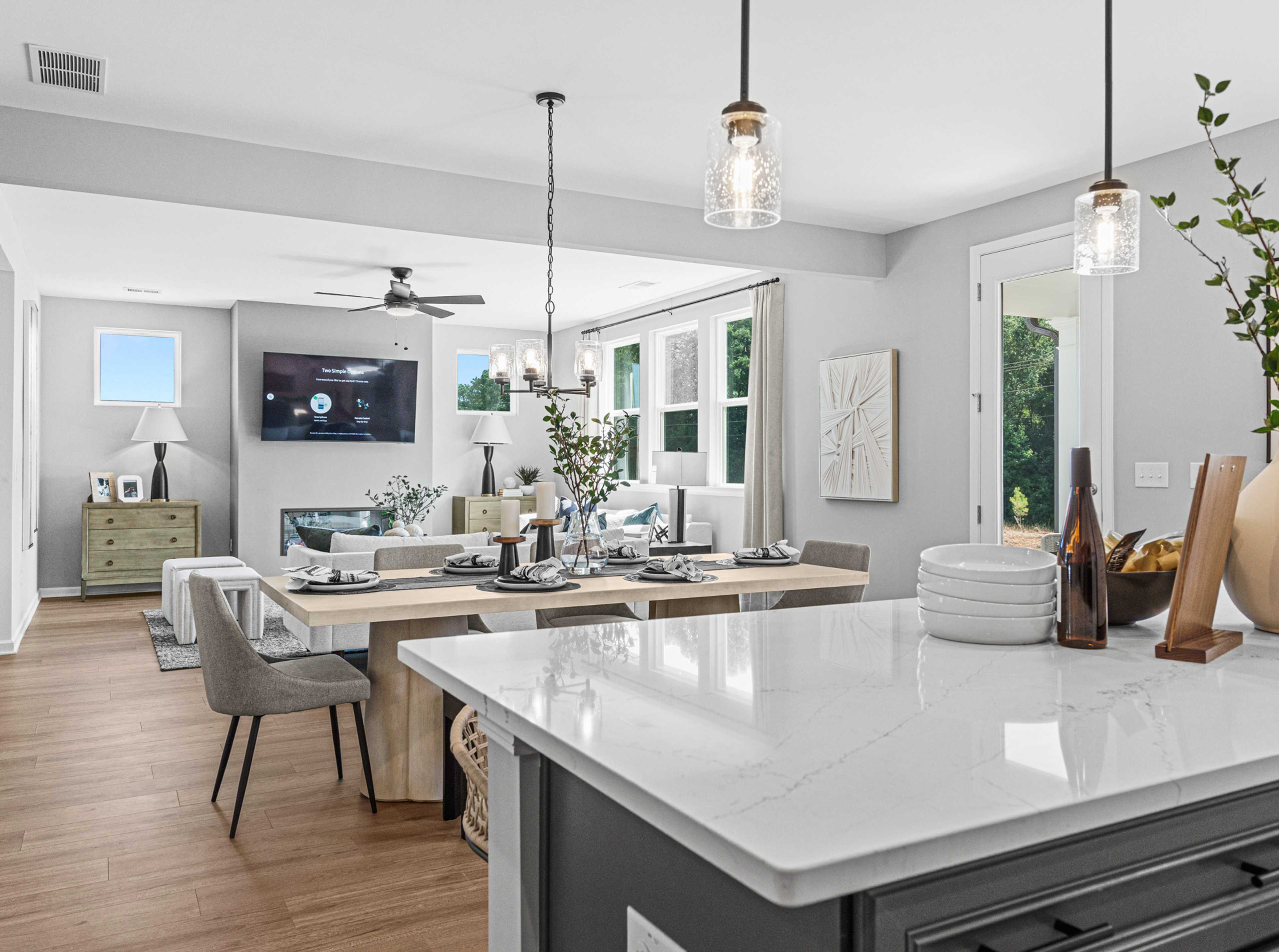Open-concept kitchen dining living area in Fern Hollow Buford GA with white quartz island hardwood floors pendant lights