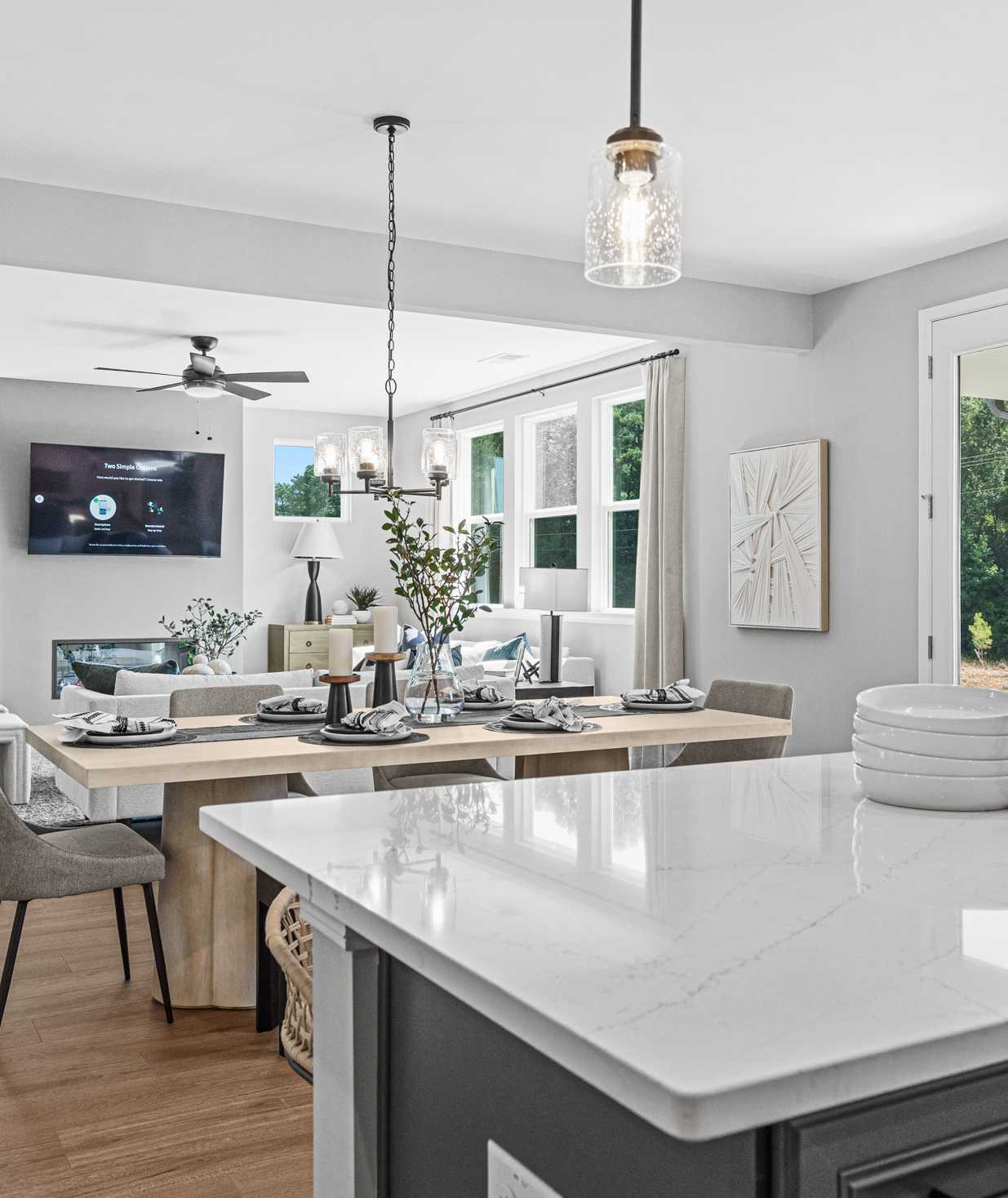 Open-concept kitchen dining living area in Fern Hollow Buford GA with white quartz island hardwood floors pendant lights