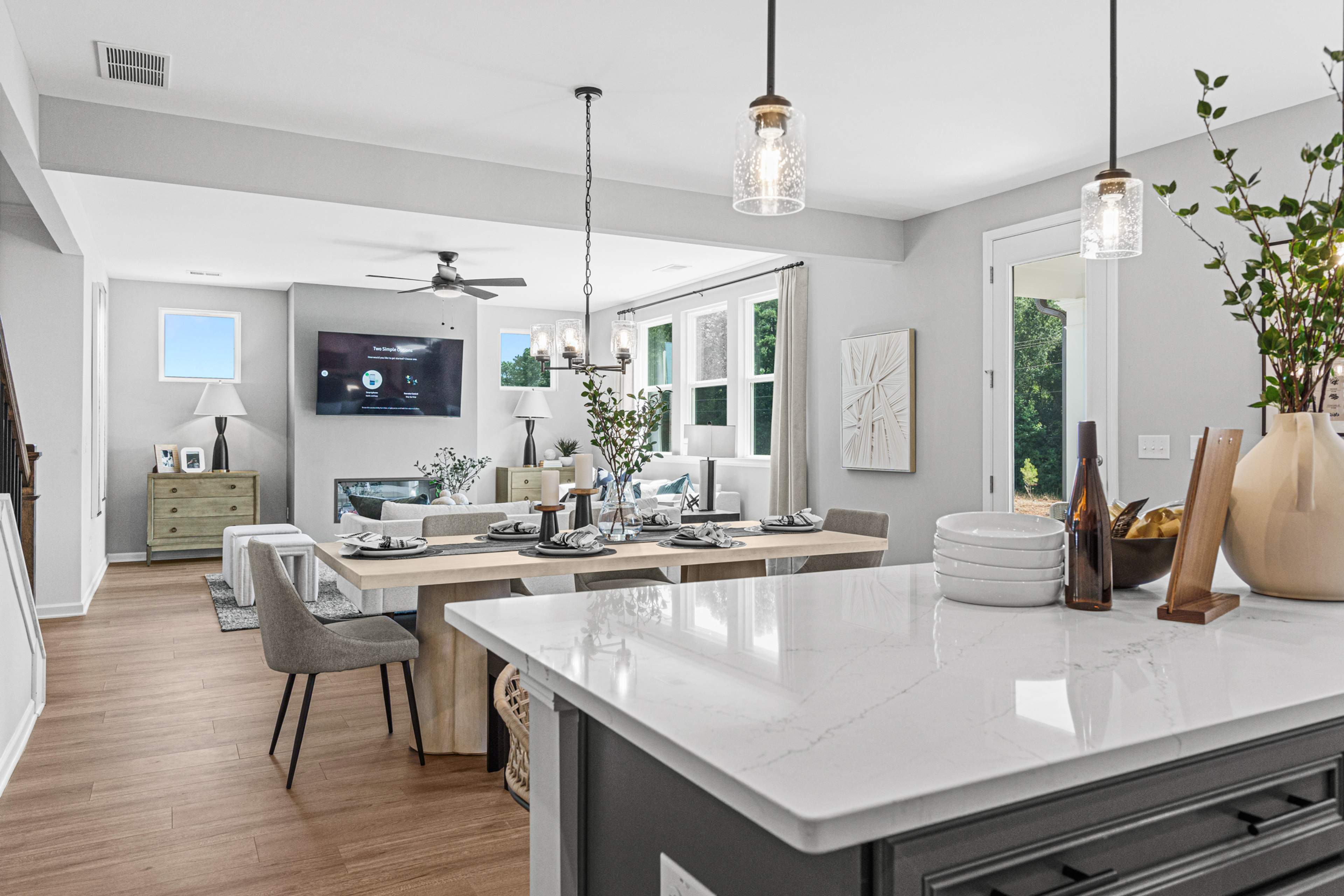 Open-concept kitchen dining living area in Fern Hollow Buford GA with white quartz island hardwood floors pendant lights