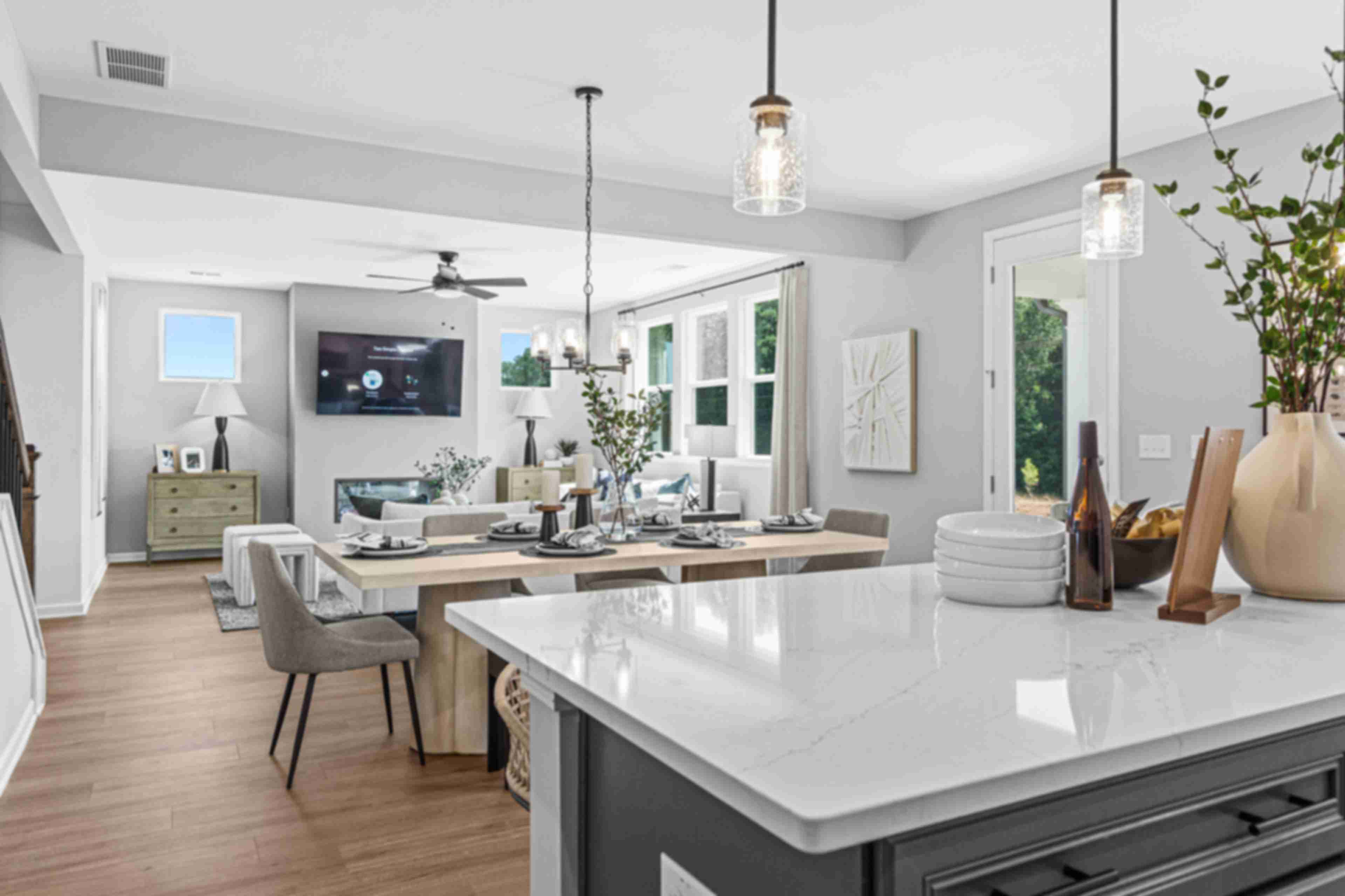 Open-concept kitchen dining living area in Fern Hollow Buford GA with white quartz island hardwood floors pendant lights