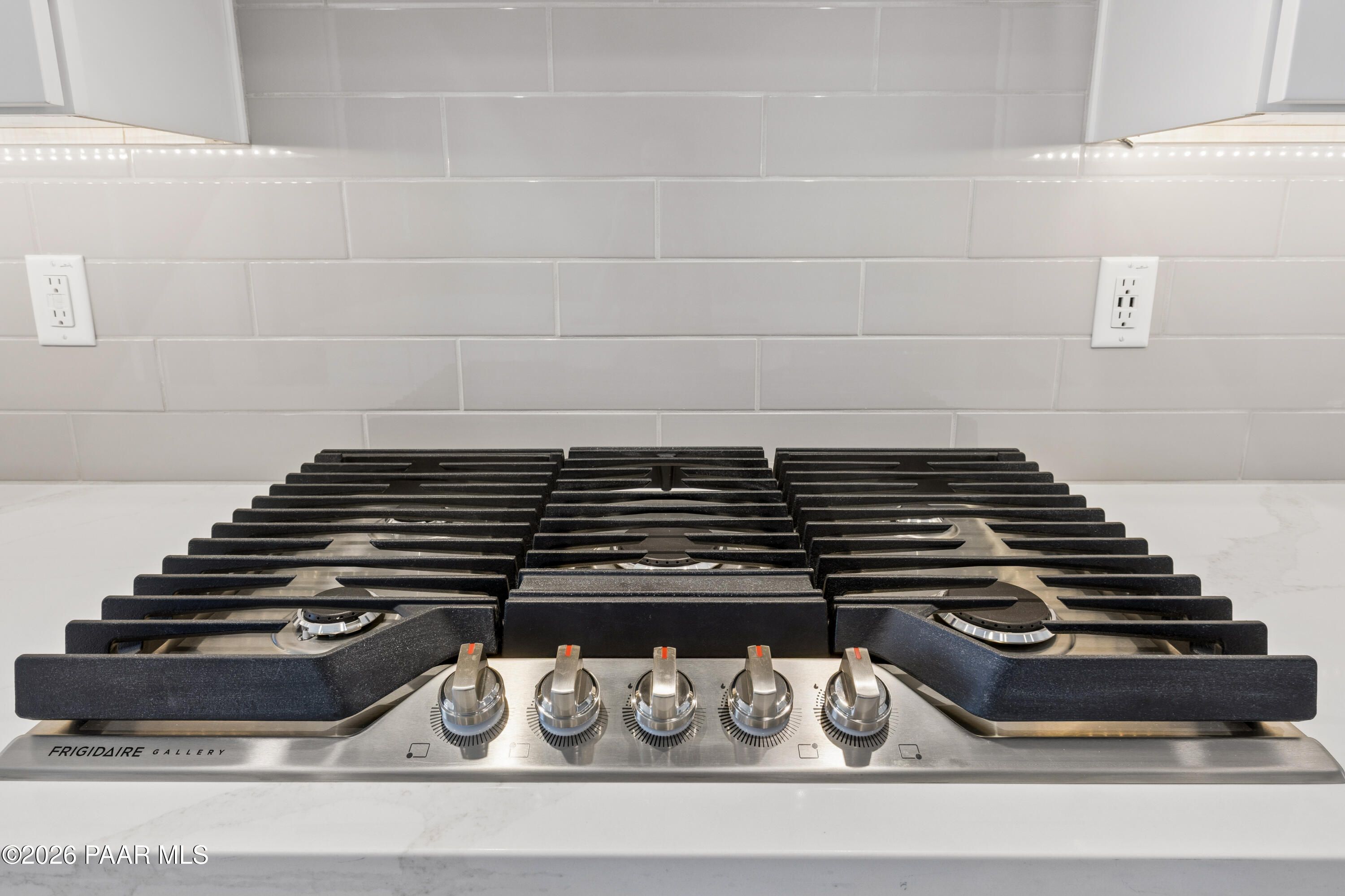 Modern stainless steel gas range with multiple burners and gray subway tile backsplash in Davidson Homes The Harmony A kitchen, Prescott Valley, AZ