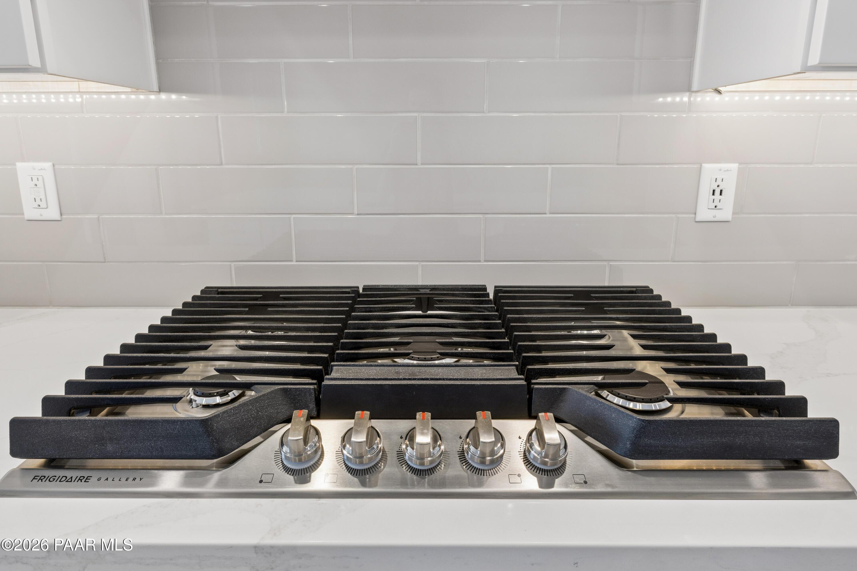 Modern stainless steel gas range with multiple burners and gray subway tile backsplash in Davidson Homes The Harmony A kitchen, Prescott Valley, AZ