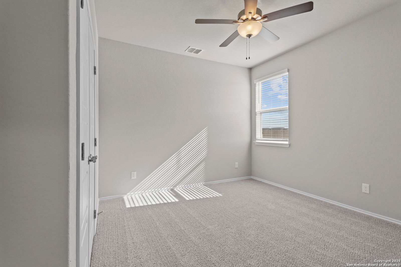 Bright secondary bedroom with ceiling fan, window blinds, and closet doors in Davidson Homes The Collin B, Seguin, Texas