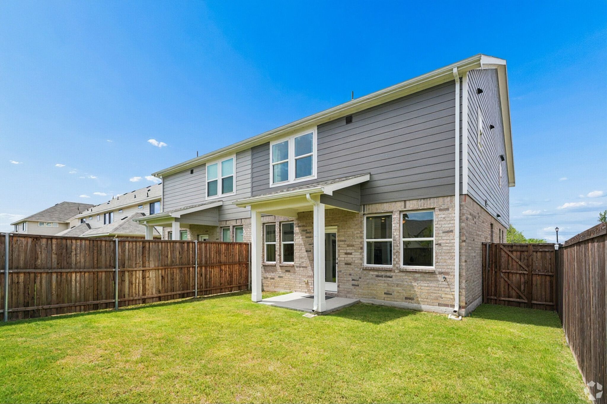 Private townhome backyard with grass, covered patio and fence