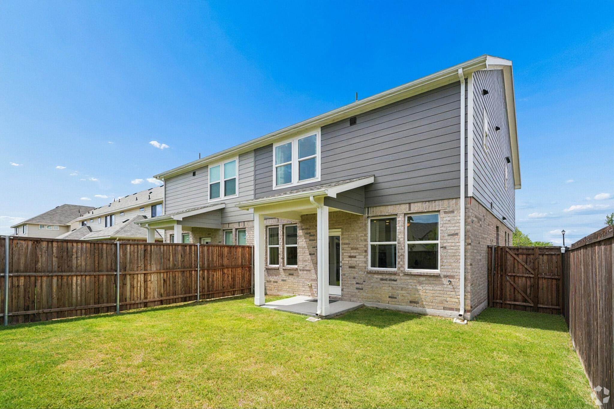 Private townhome backyard with grass, covered patio and fence