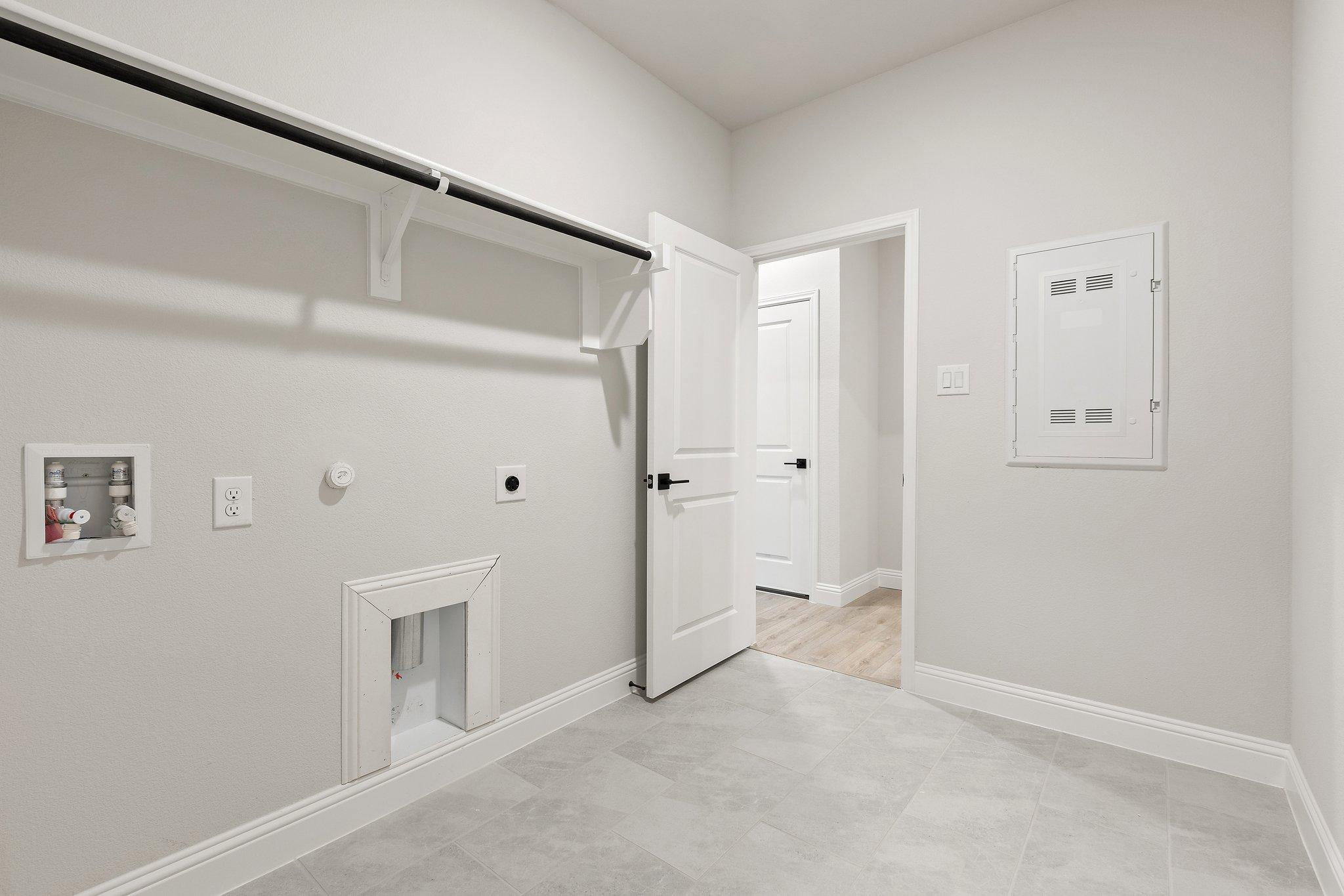 Spacious laundry room in The Harrison home with washer dryer hookups, built-in shelves, and neutral tones