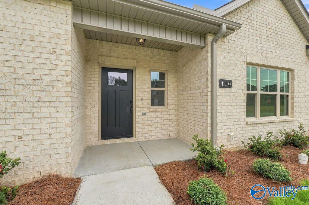 Cream brick exterior with covered front porch and black front door of The Camilla C home in The Retreat at Cain Park.