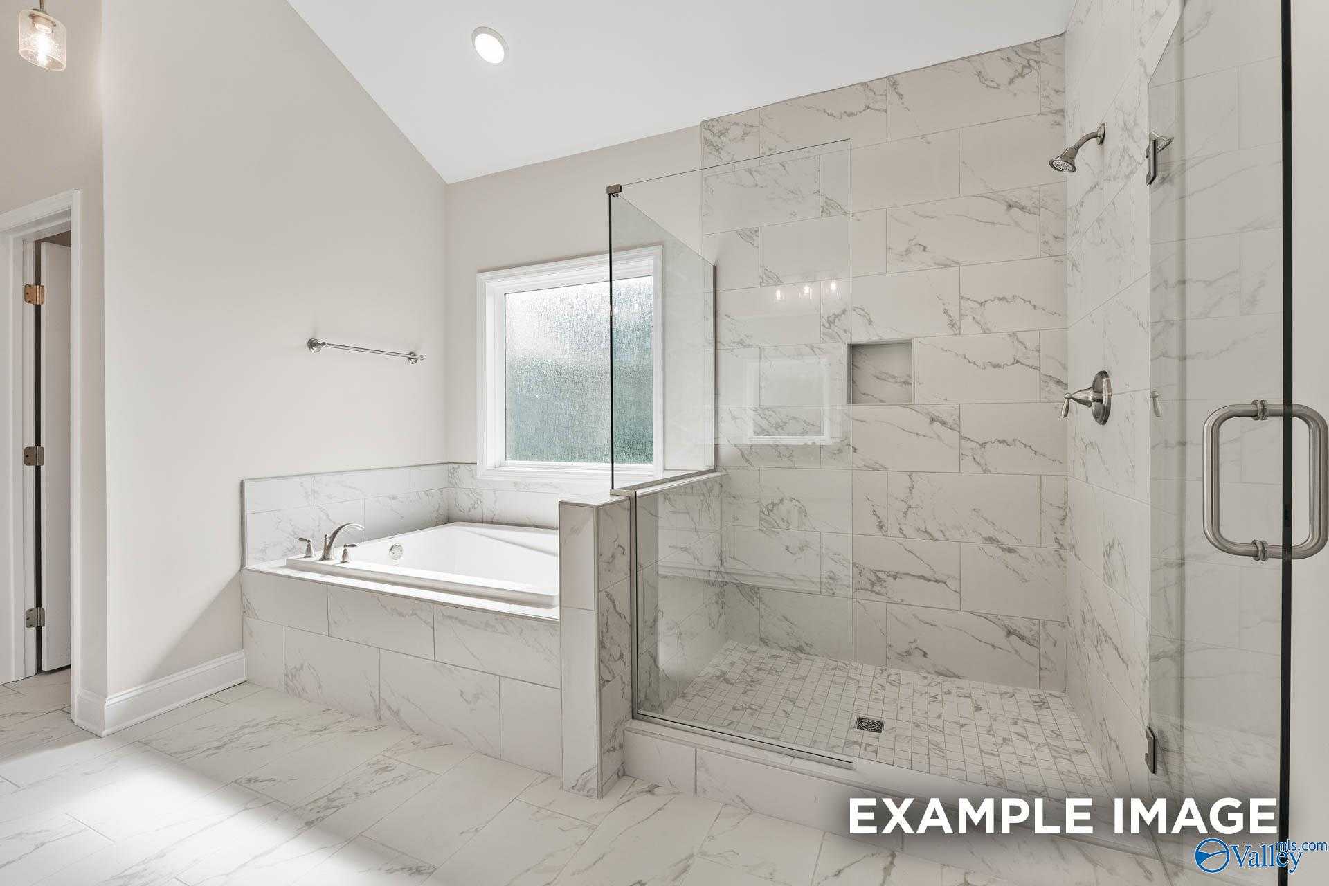 Luxurious master bathroom with freestanding soaking tub, glass shower, and marble tiles in Davidson Homes The Finleigh, Meridianville, Alabama