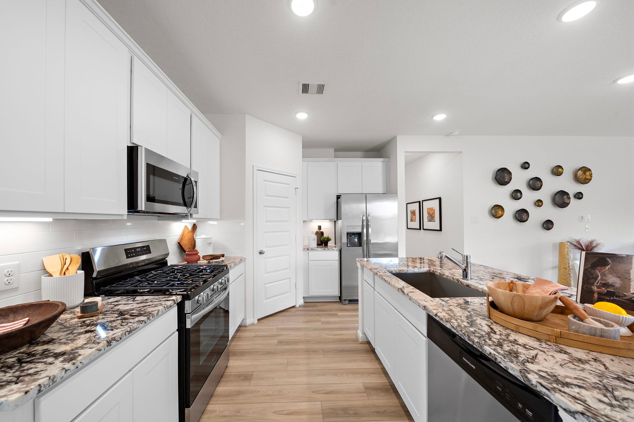 Spacious modern kitchen with white cabinets, stainless steel appliances, granite counters and hardwood floors at The Villages at WestPointe in Dayton Texas