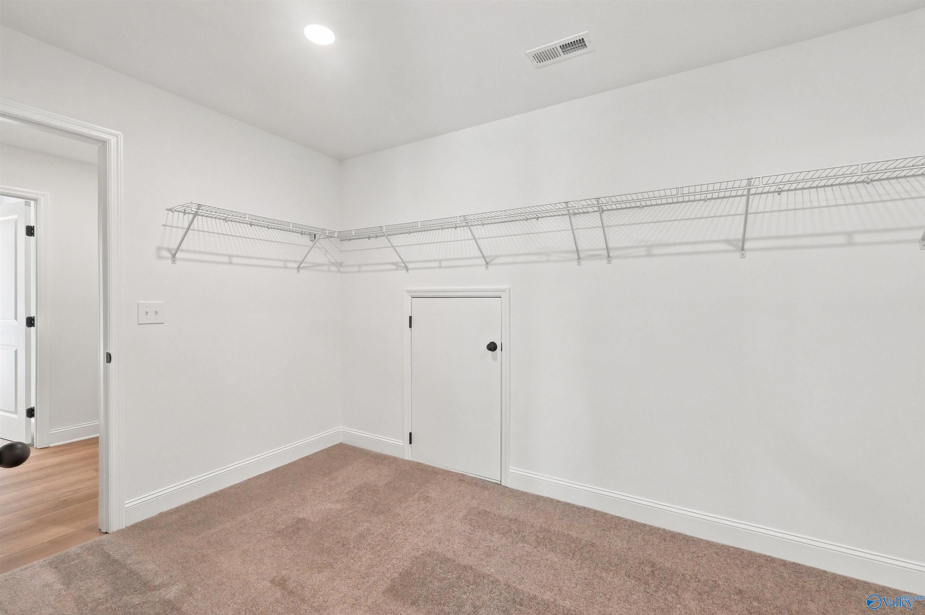 Walk-in closet with wire shelving and additional storage access in The Chelsea C floor plan, Creek Grove, New Market, AL.