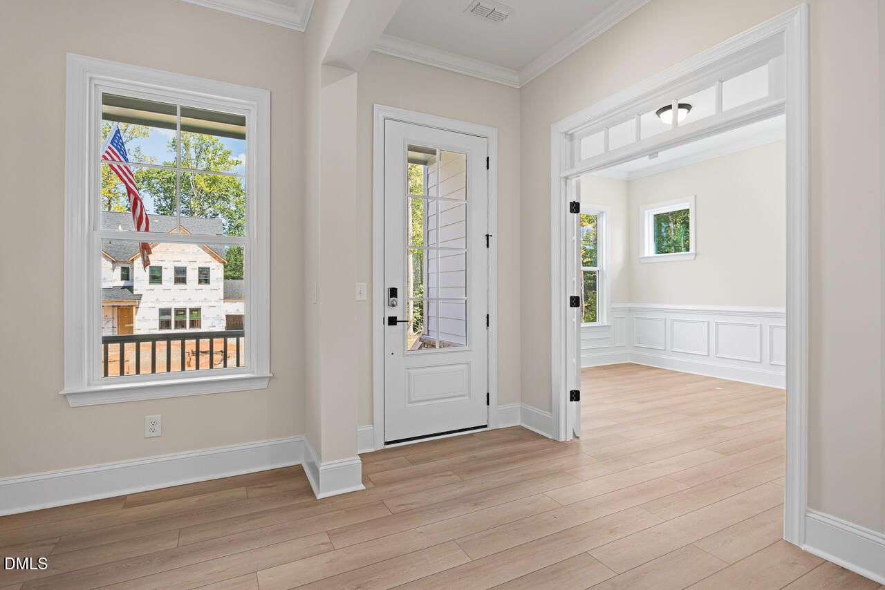 Bright foyer with glass-panel front door, hardwood floors, and wainscoting in Davidson Homes Crawford D plan, Wake Forest, NC