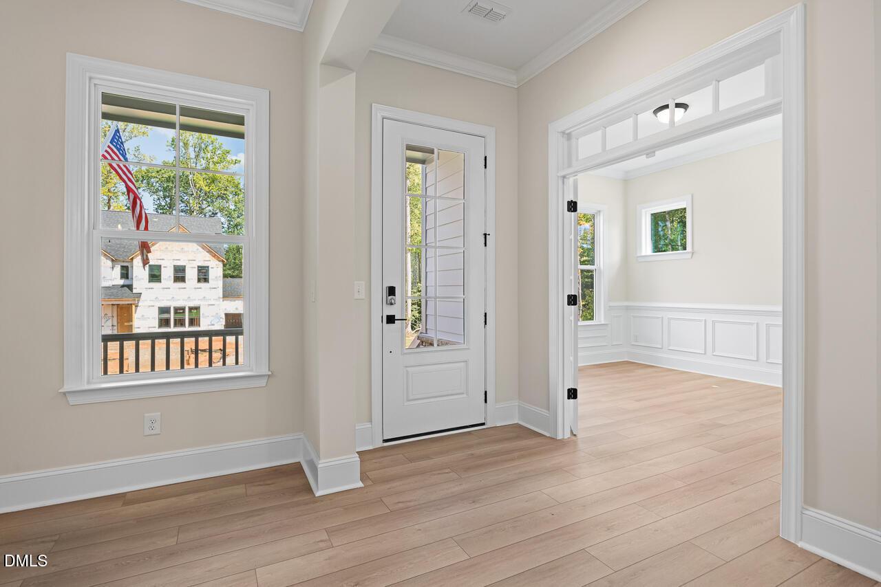 Bright foyer with glass-panel front door, hardwood floors, and wainscoting in Davidson Homes Crawford D plan, Wake Forest, NC