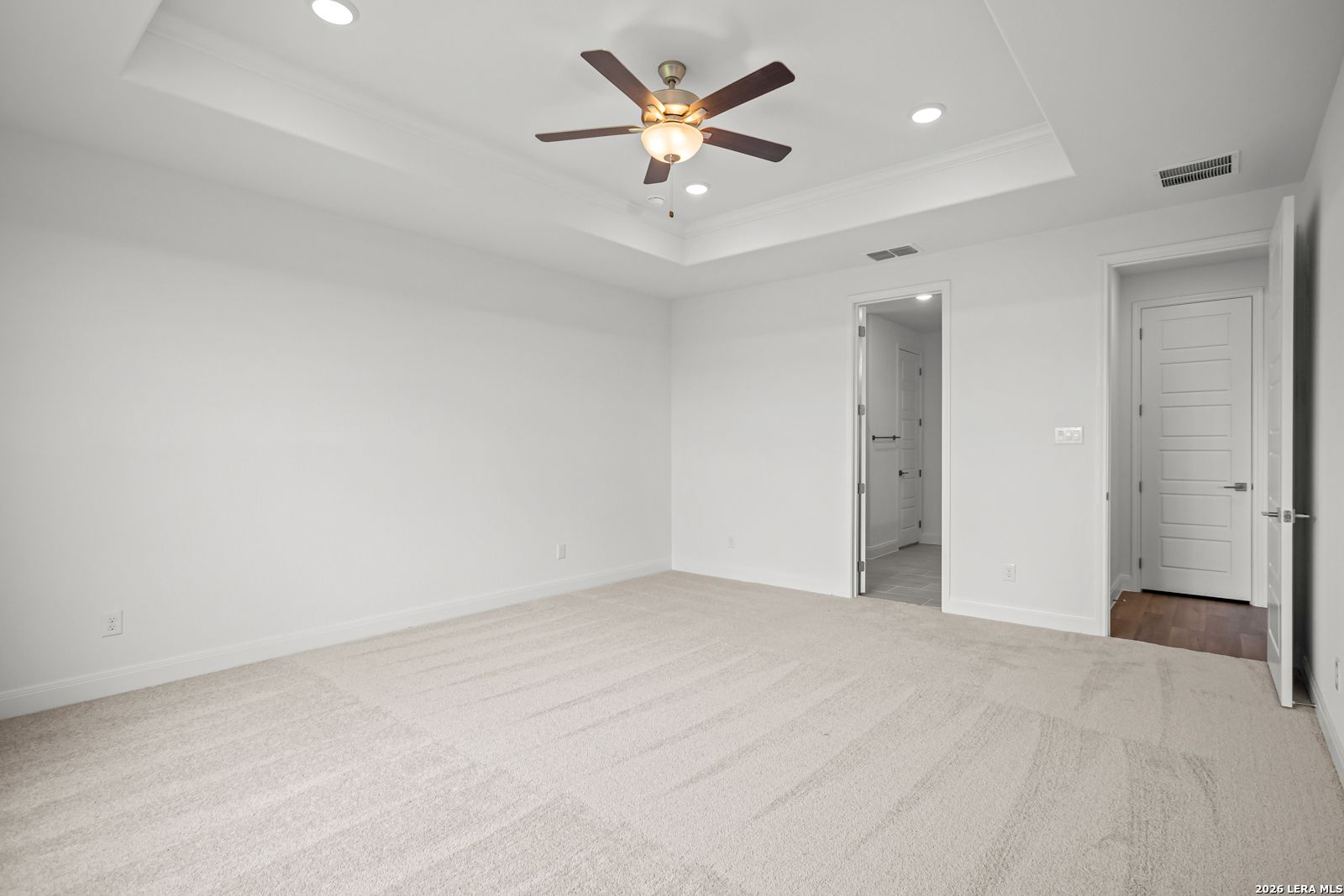 Bright primary bedroom with tray ceiling and ceiling fan in The Lanier G floor plan at The Reserve at Potranco Oaks.