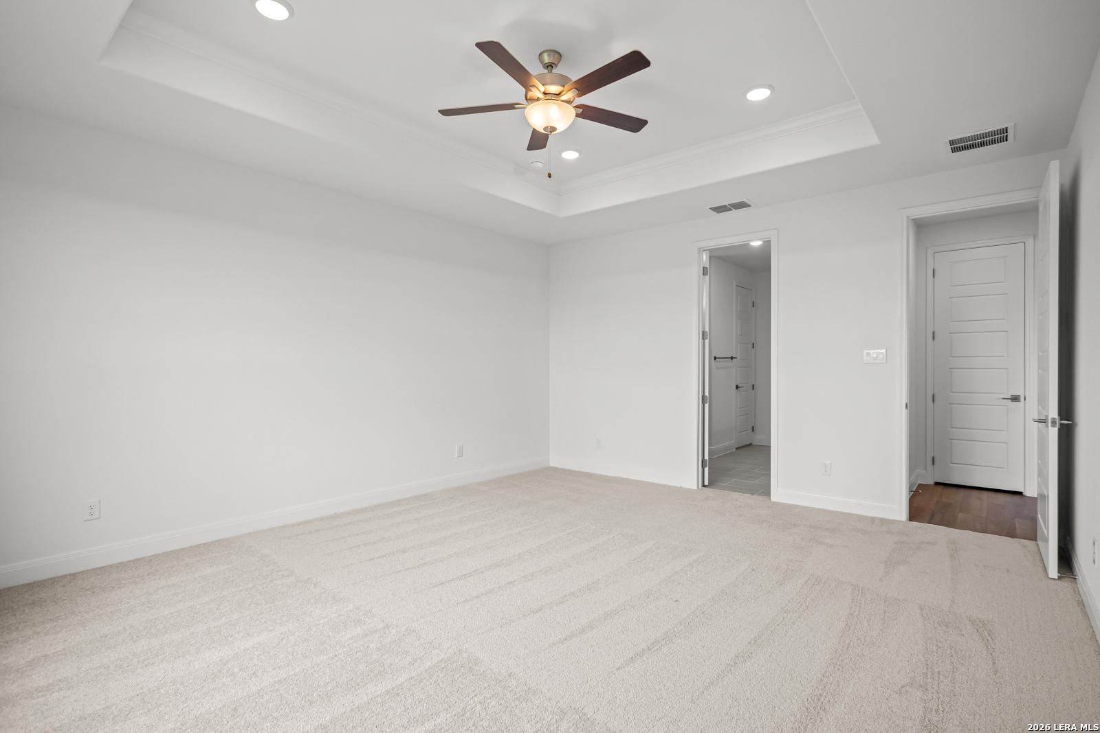 Bright primary bedroom with tray ceiling and ceiling fan in The Lanier G floor plan at The Reserve at Potranco Oaks.