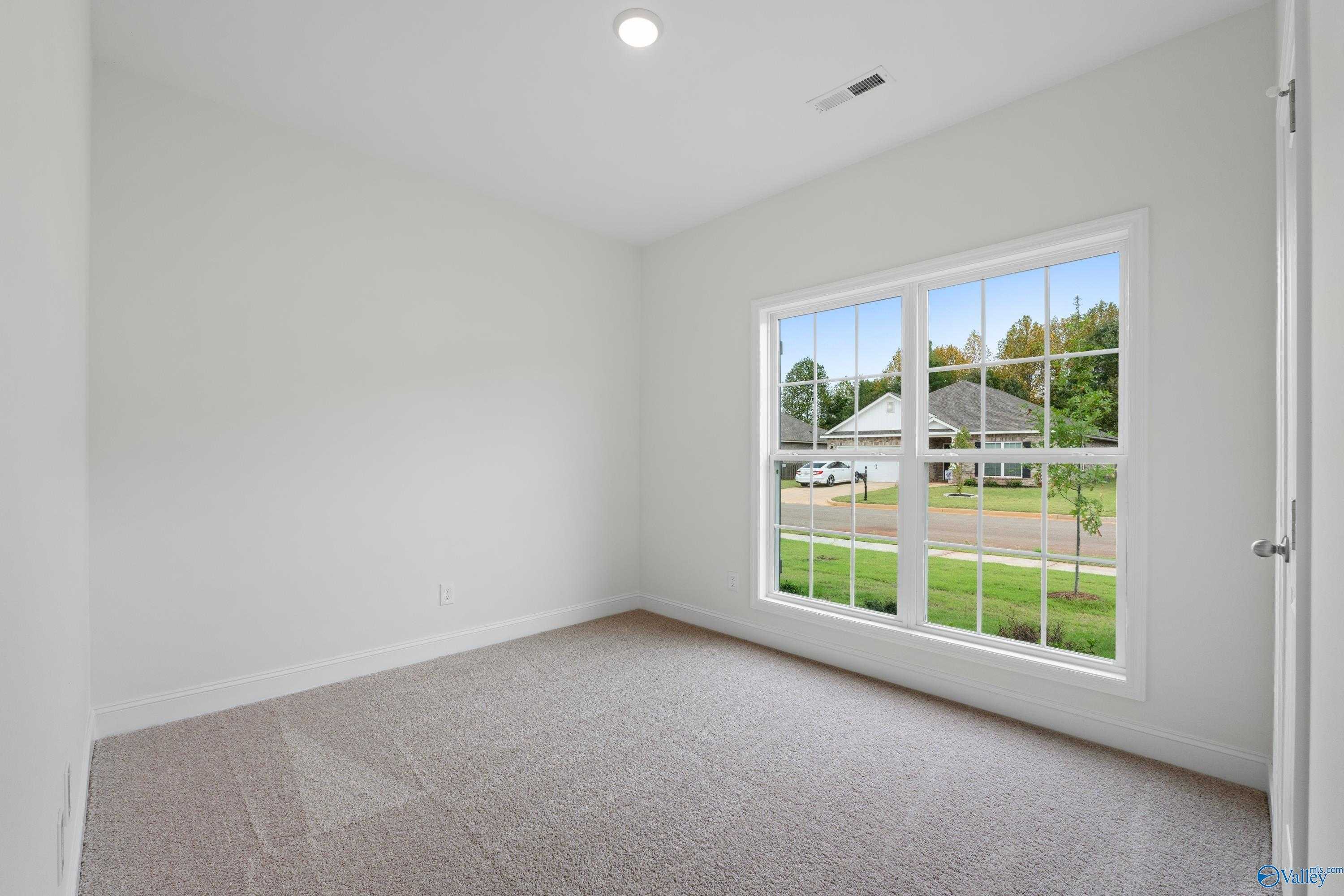 Empty bedroom with large windows overlooking suburban neighborhood in Davidson Homes The Asheville C, Athens, Alabama