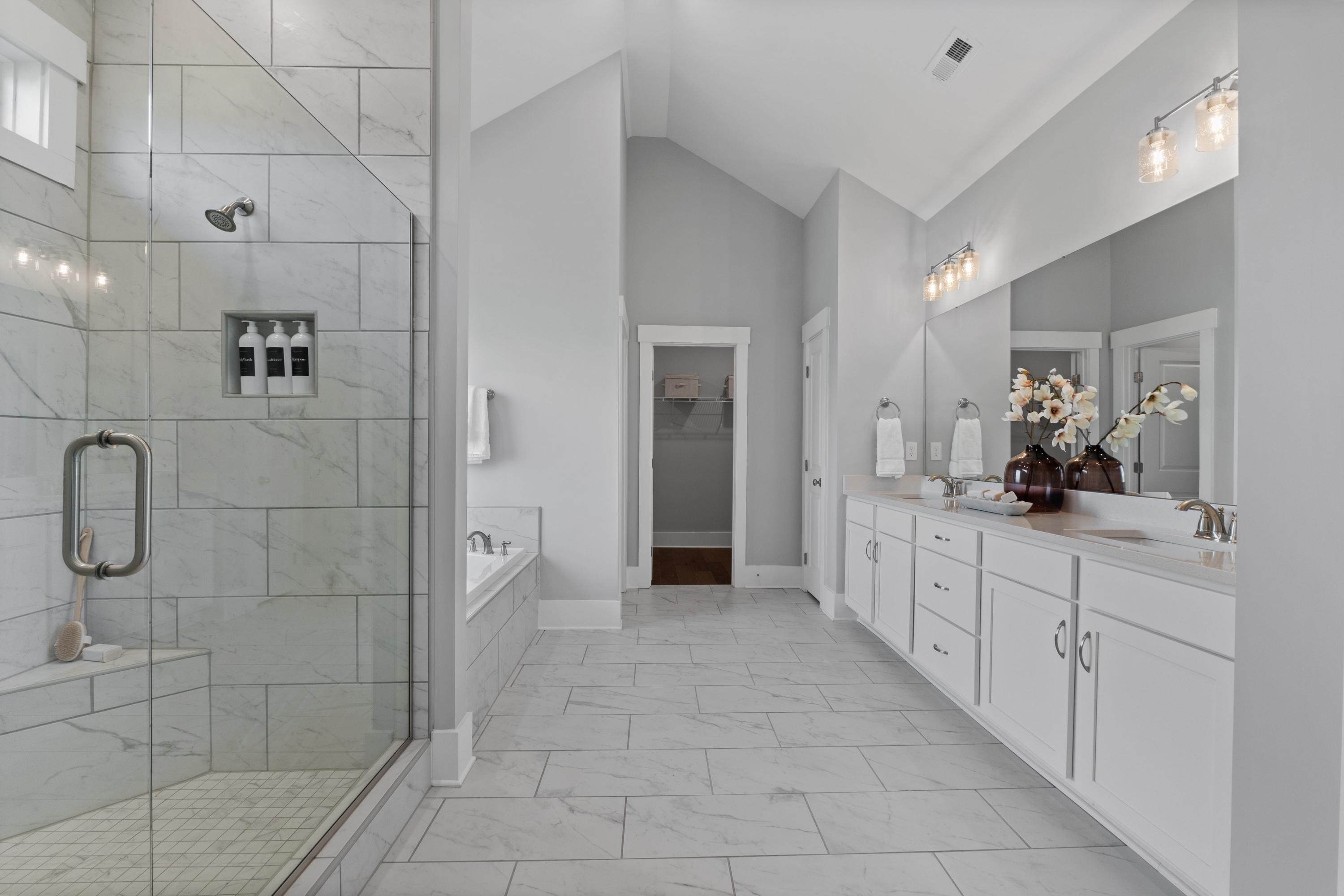 Spacious master bathroom in Creekside Harvest Alabama with glass shower, freestanding tub, double vanity, and tiled floors