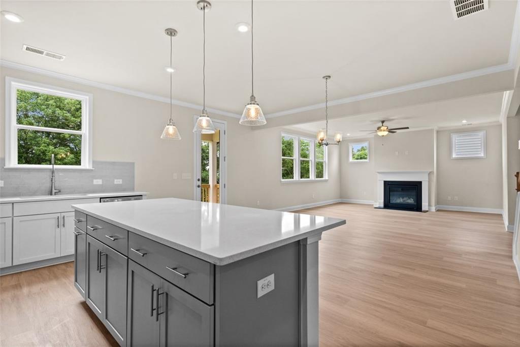 Modern open-concept kitchen with white quartz island, gas fireplace, and large windows in The Hickory B home at Wehunt Meadows, Hoschton