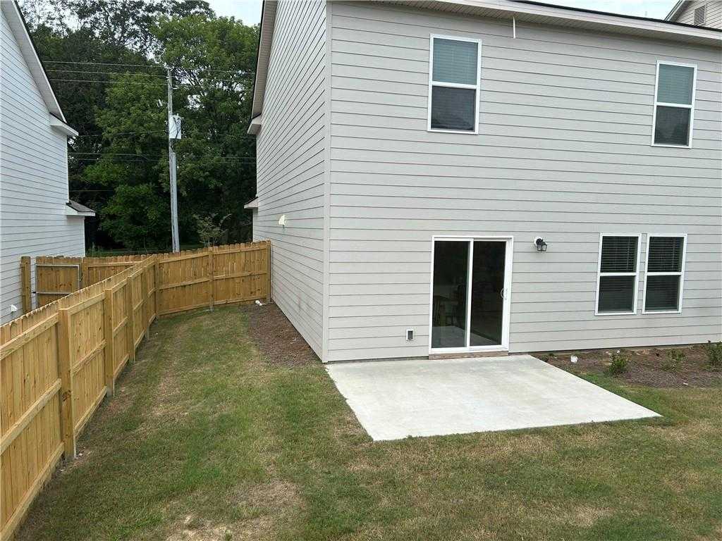 Rear view of The Bartlett 2-story home with sliding glass doors, concrete patio, and fenced backyard in Summer Vineyard, Phenix City, Alabama