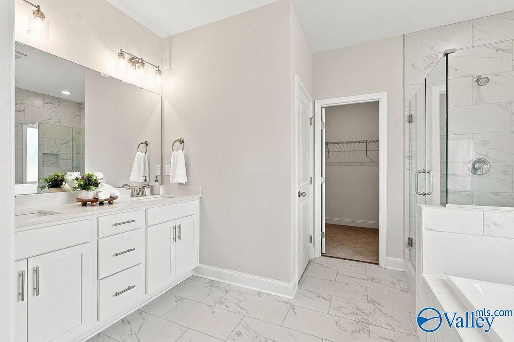 Elegant master bathroom with white vanity, marble tile floors, glass walk-in shower, and soaking tub in Davidson Homes The Harrison plan