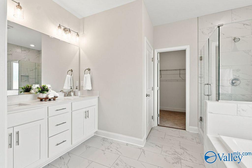 Elegant master bathroom with white vanity, marble tile floors, glass walk-in shower, and soaking tub in Davidson Homes The Harrison plan