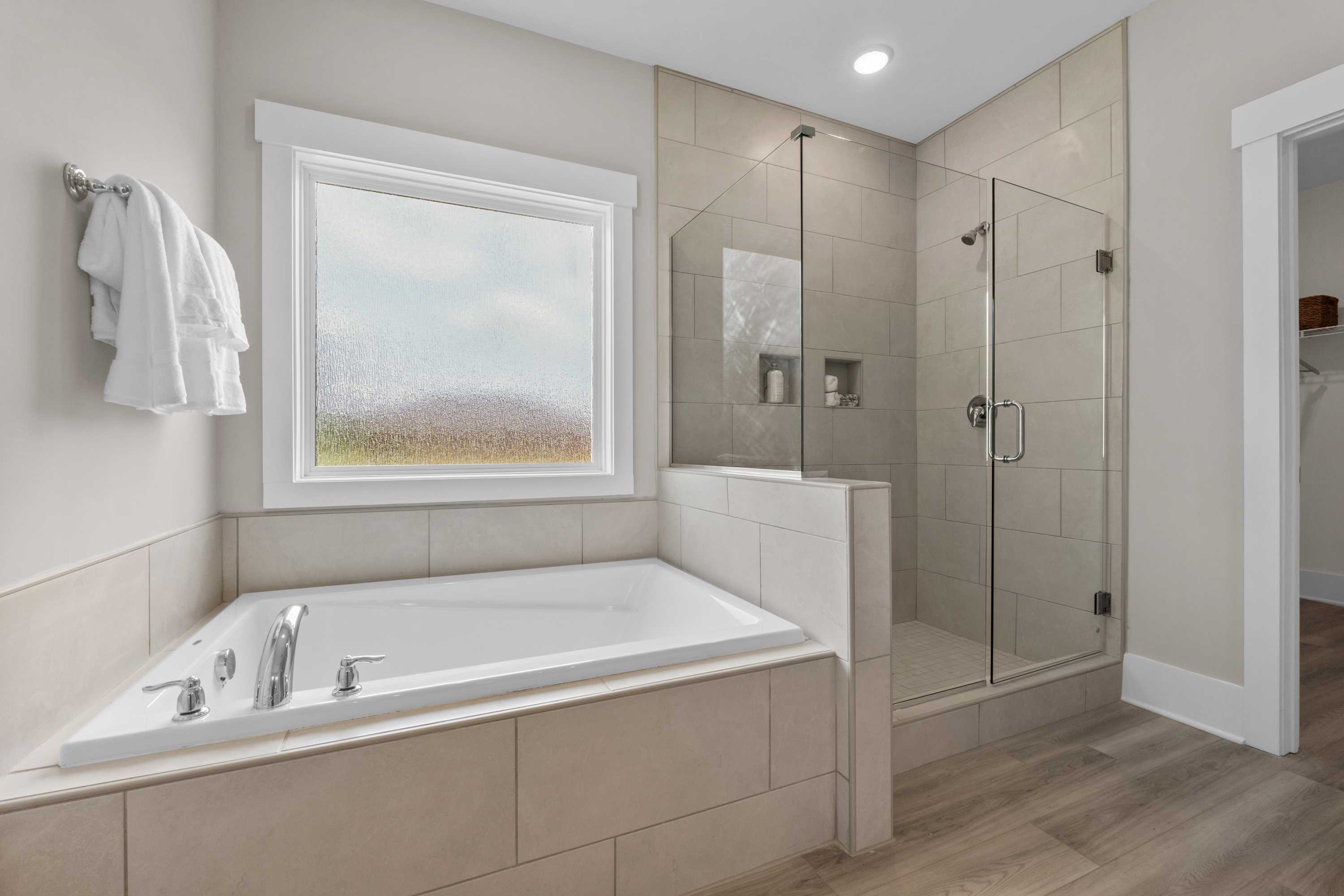 Spacious master bathroom at The Highlands in Arab, Alabama with freestanding tub, glass shower, and neutral tile floors