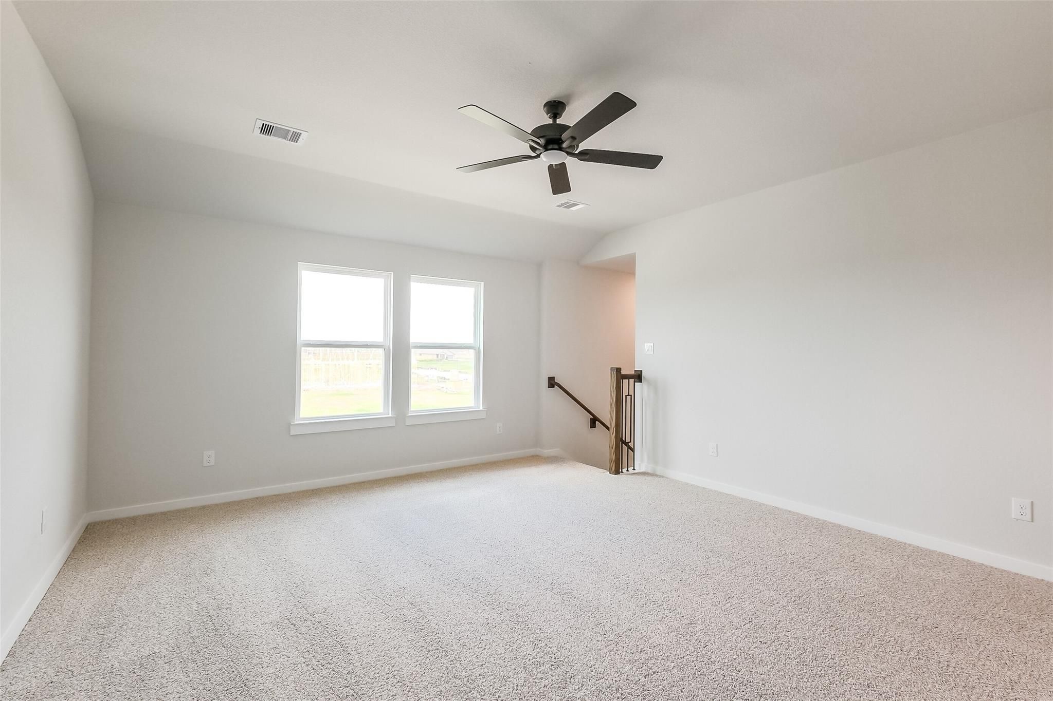 Bright upstairs loft with large windows, ceiling fan, and carpeted flooring in Davidson Homes The Tierra B, Beasley, Texas