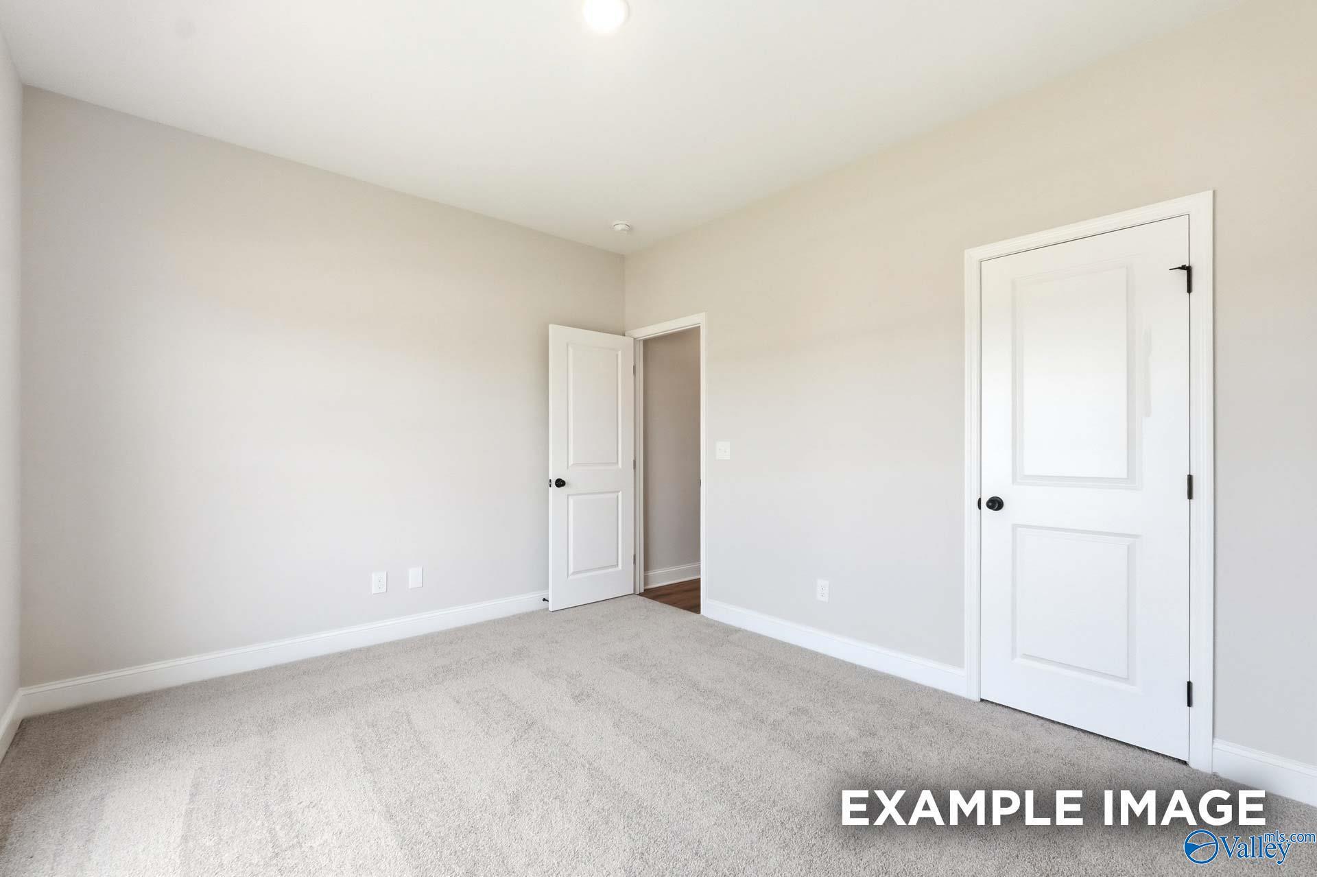 Neutral carpeted bedroom with white doors in The Daphne floor plan by Davidson Homes in Clearview, Hazel Green, Alabama.
