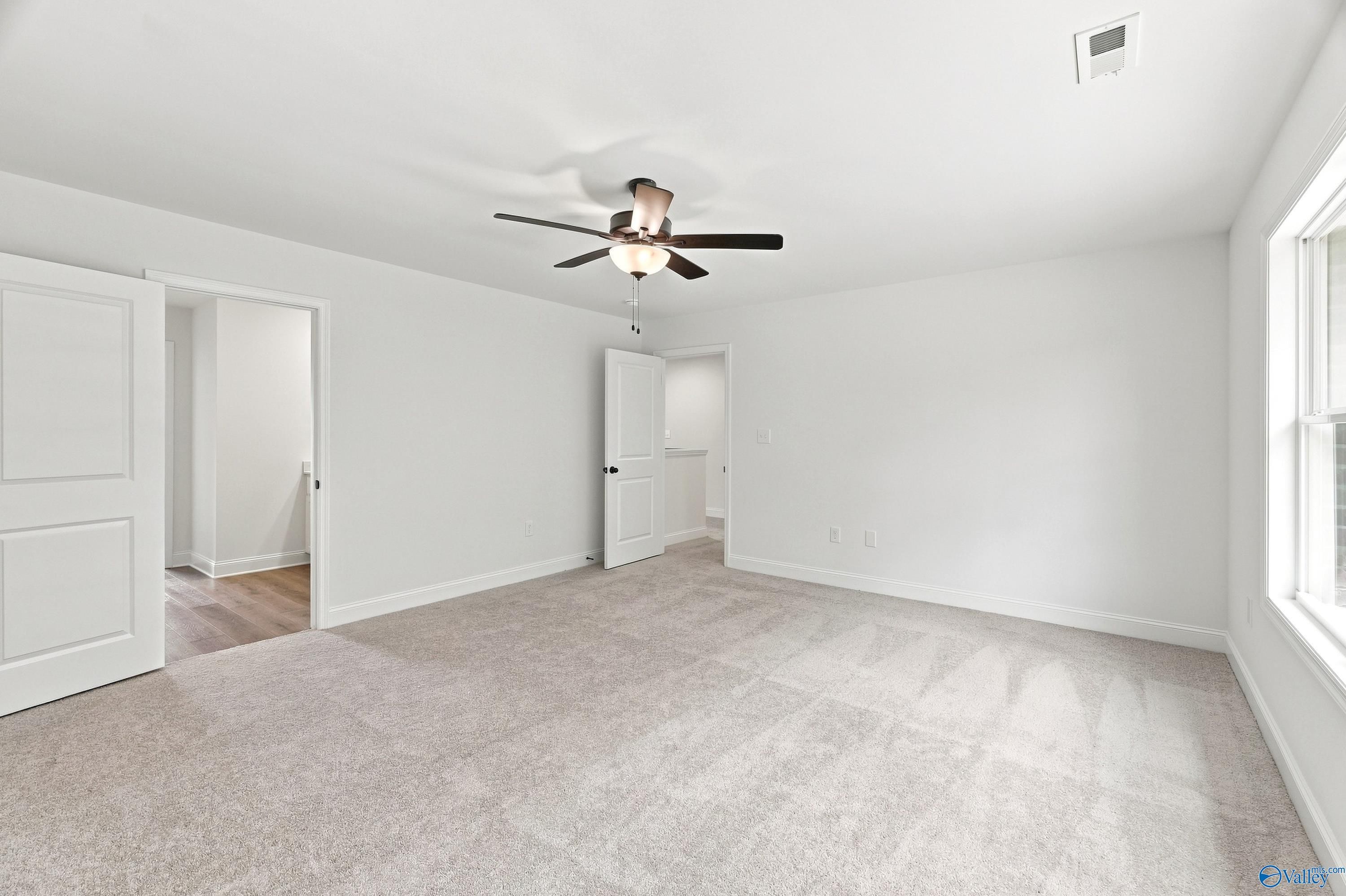 Spacious carpeted bedroom with ceiling fan in The Shelby B floor plan at Jaguar Hills, Huntsville, Alabama.