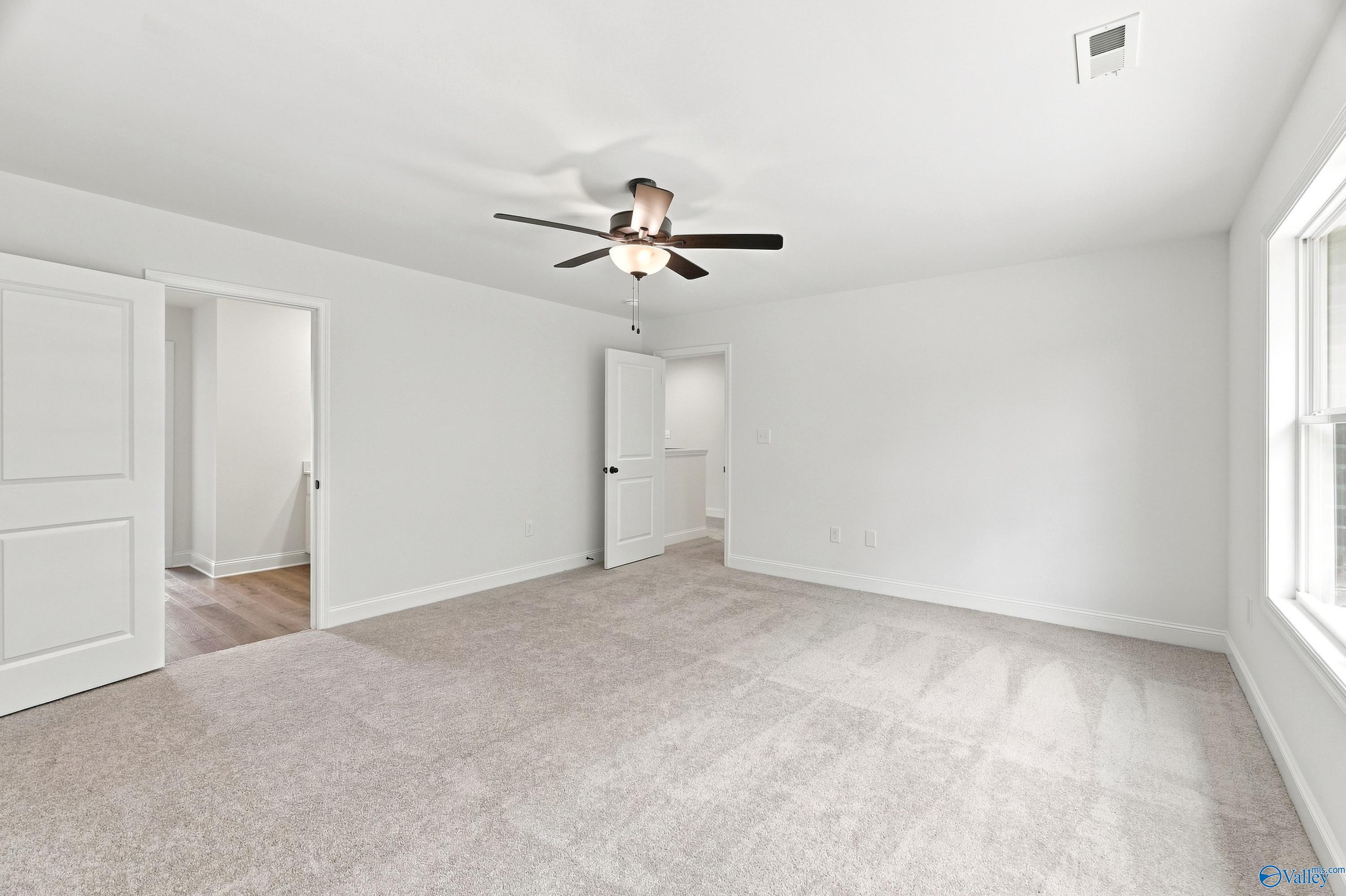 Spacious carpeted bedroom with ceiling fan in The Shelby B floor plan at Jaguar Hills, Huntsville, Alabama.